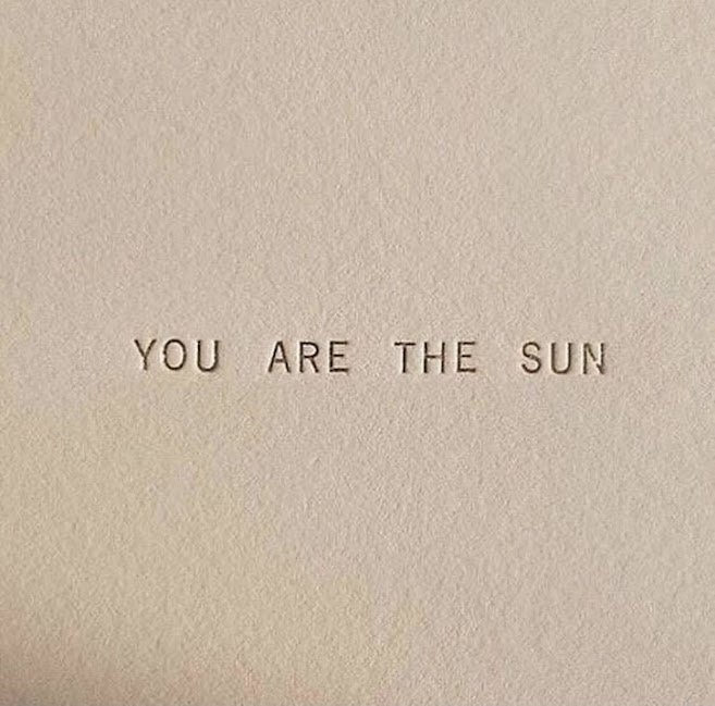 The phrase 'YOU ARE THE SUN' spelled out in small, uppercase letters on a plain, light beige background.