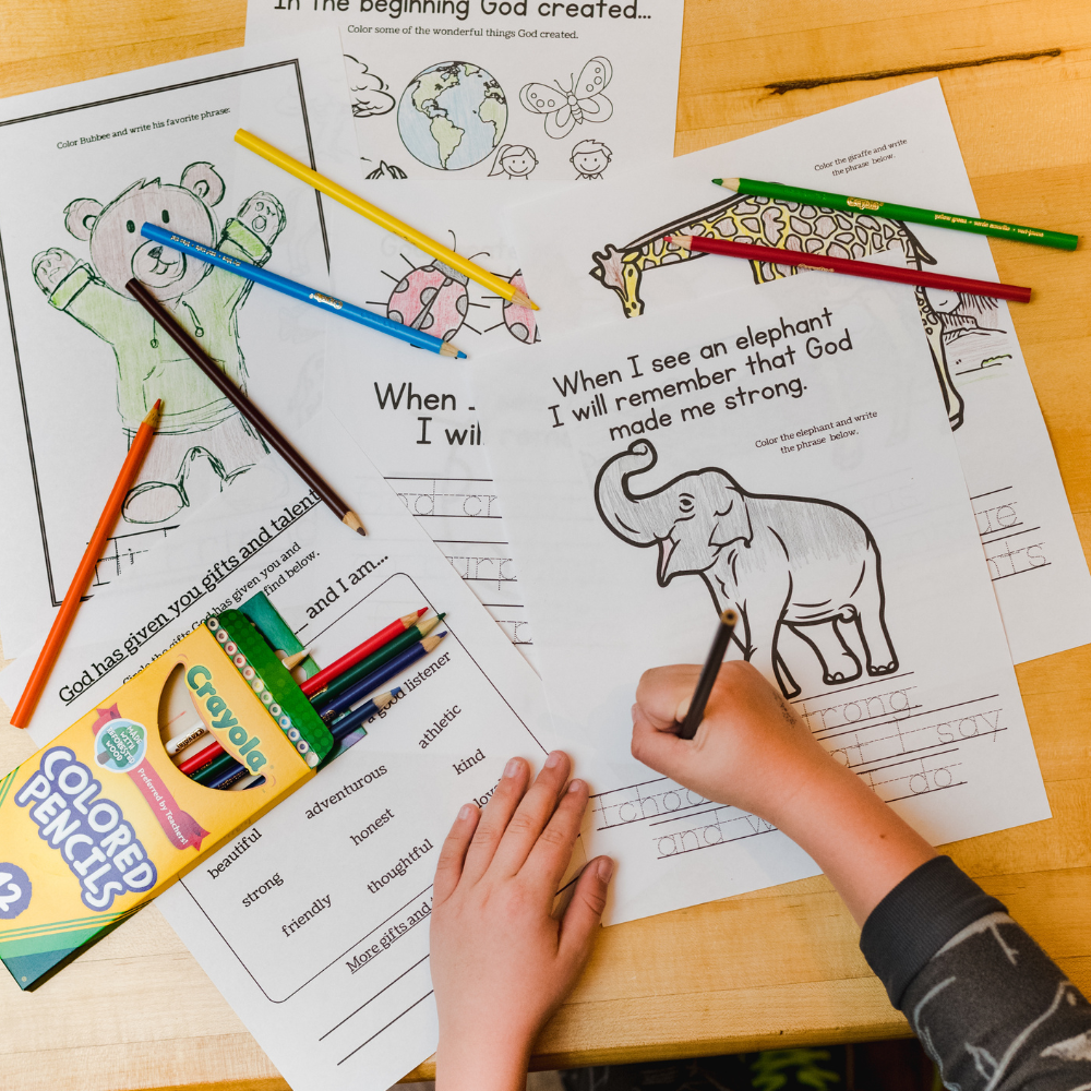 Child coloring pages on table with colored pencils