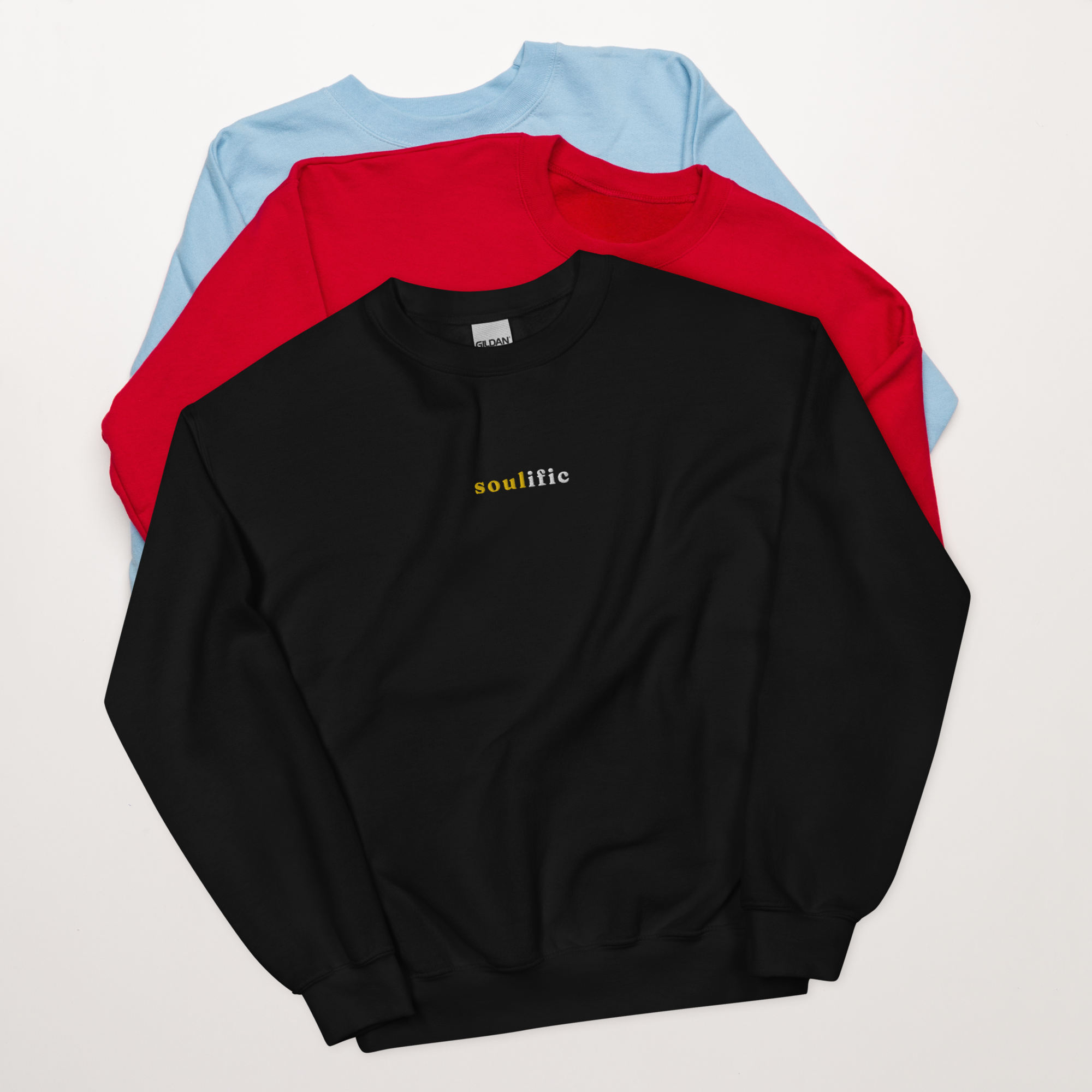 three crewneck sweatshirts, sky blue, red, and Black on top with "Soulific" on the front. Available for purchase.