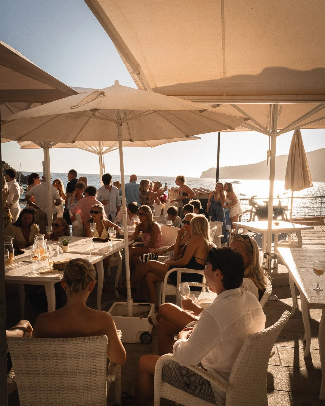 La magia de la "hora dorada" se vive intensamente en la terraza del Restaurante Es Raor en Sant Elm (Andratx). A medida que el sol desciende sobre el mar Mediterráneo, el ambiente se vuelve aún más especial. Nuestra terraza se llena de vida con clien