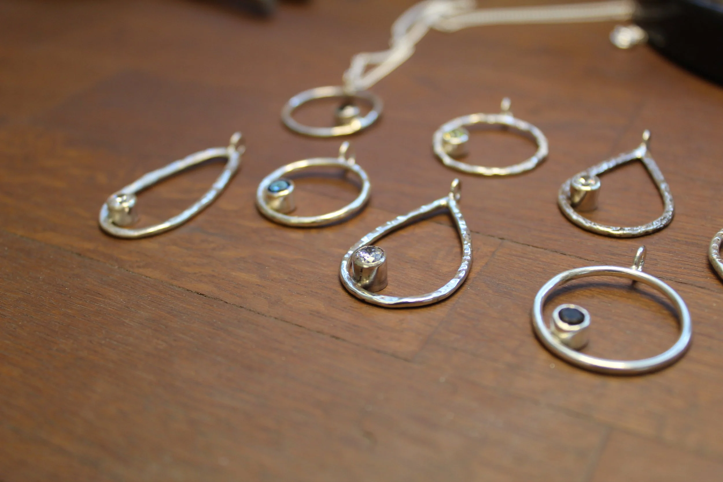 A series of different hand made recycled silver necklaces, each with a different texture and set with a different coloured gemstone