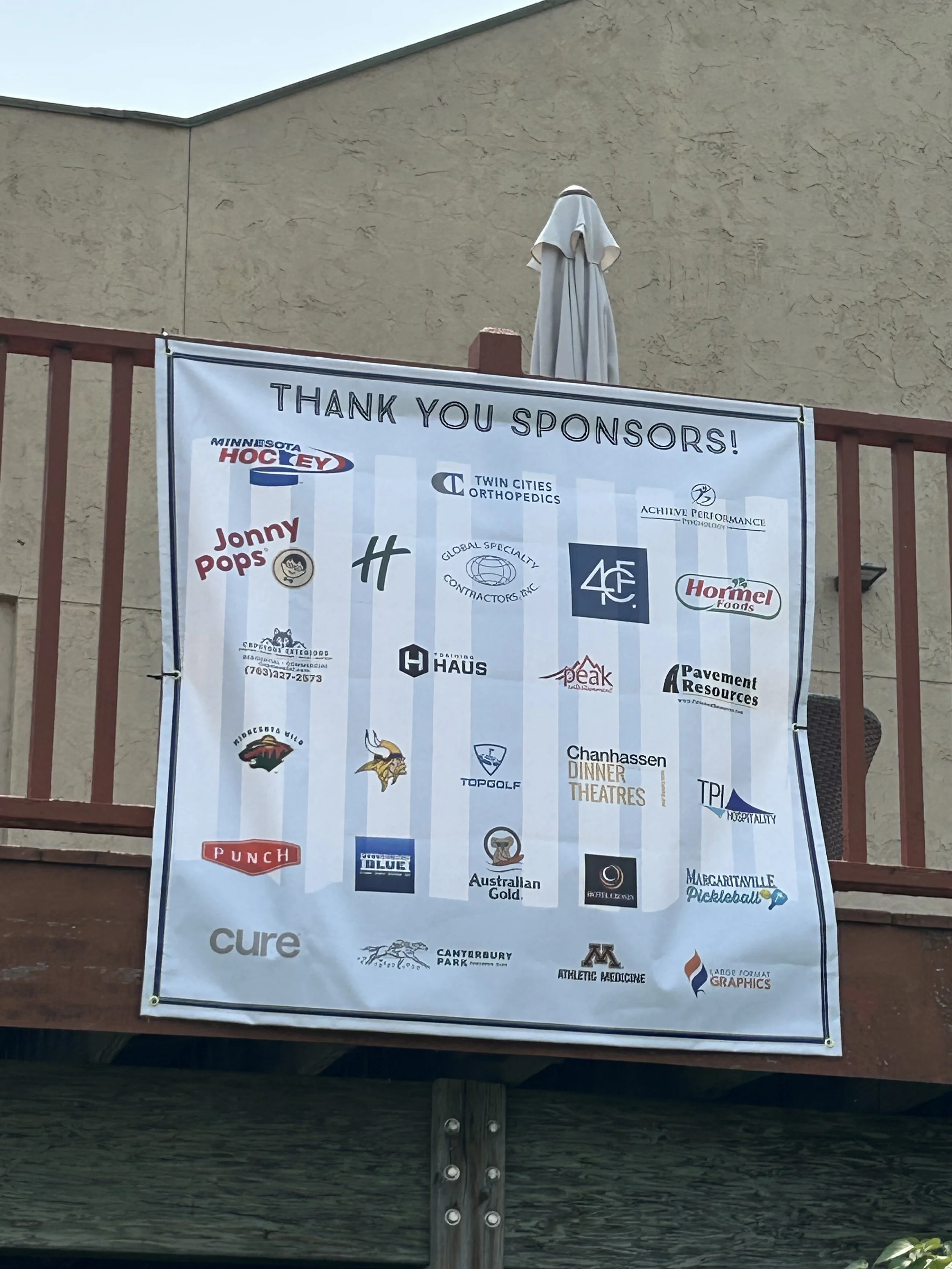 A thank you sponsors sign with a banner listing various sponsor logos and names that support executive coaching and sport psychology therapy
