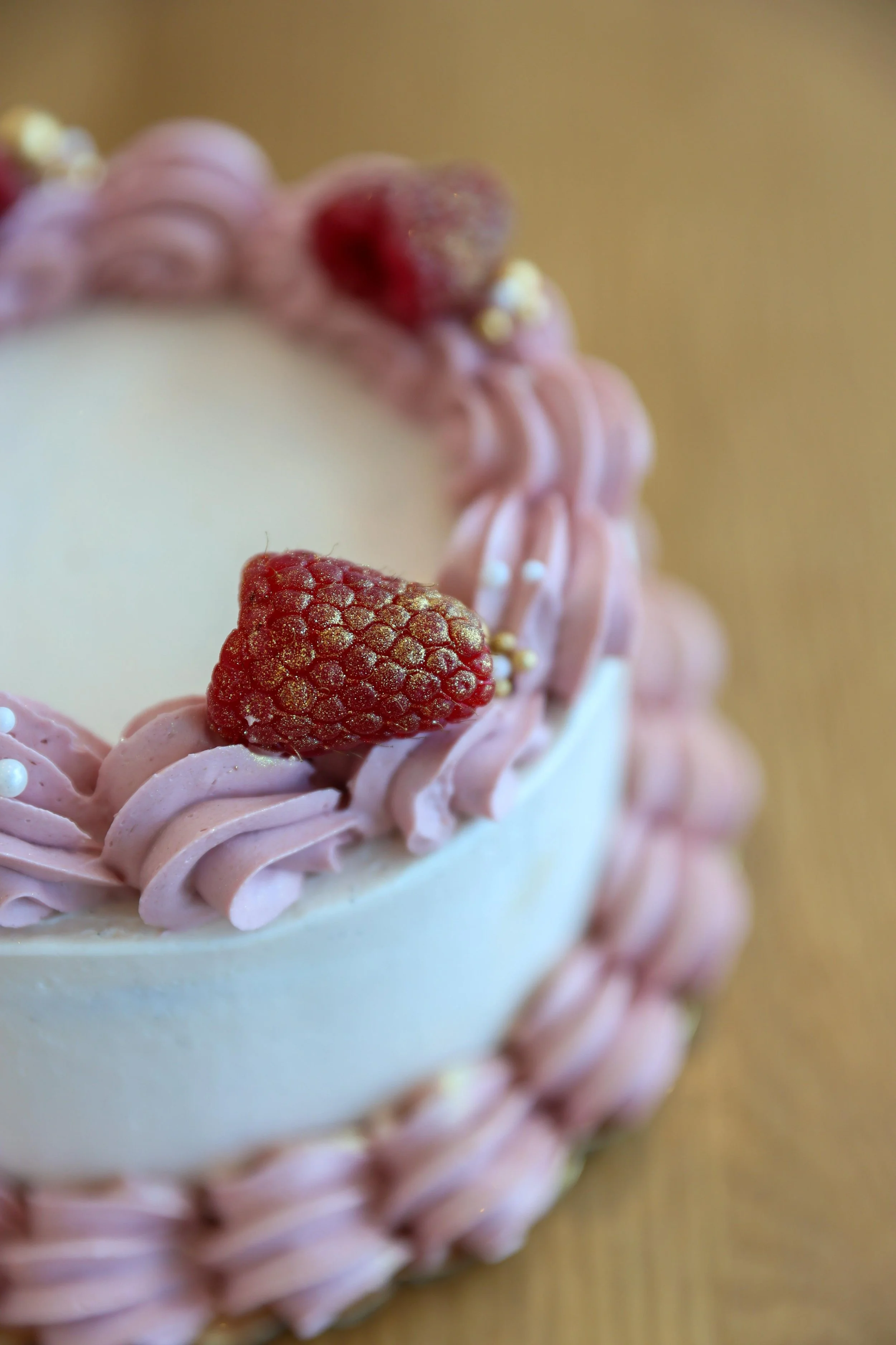 close up of a vegan lemon raspberry 4” cake on a wood table