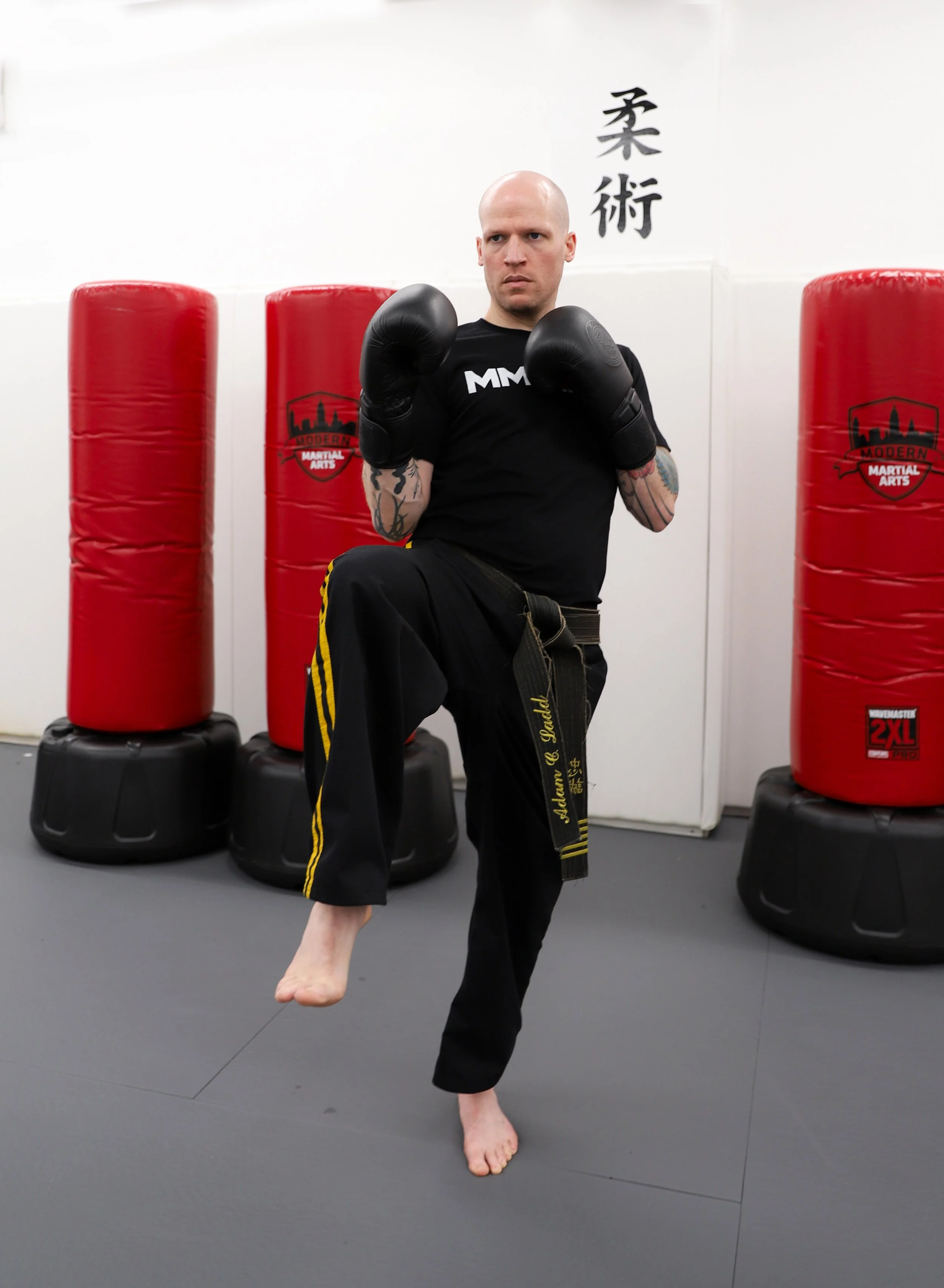 Black belt student wearing boxing gloves and kicking