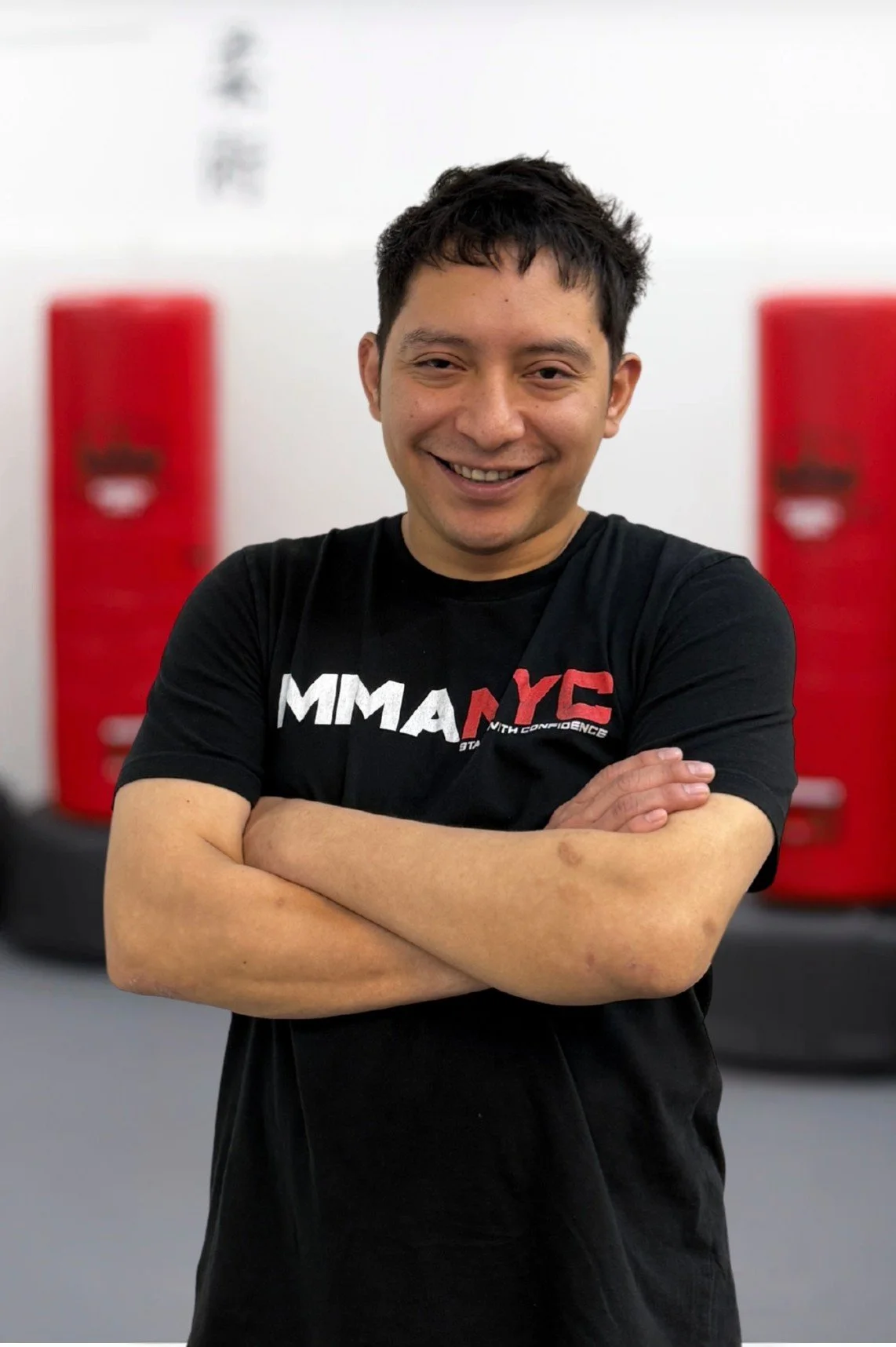 Silhouette of a ninja with swords and red punching bags in a martial arts studio background.