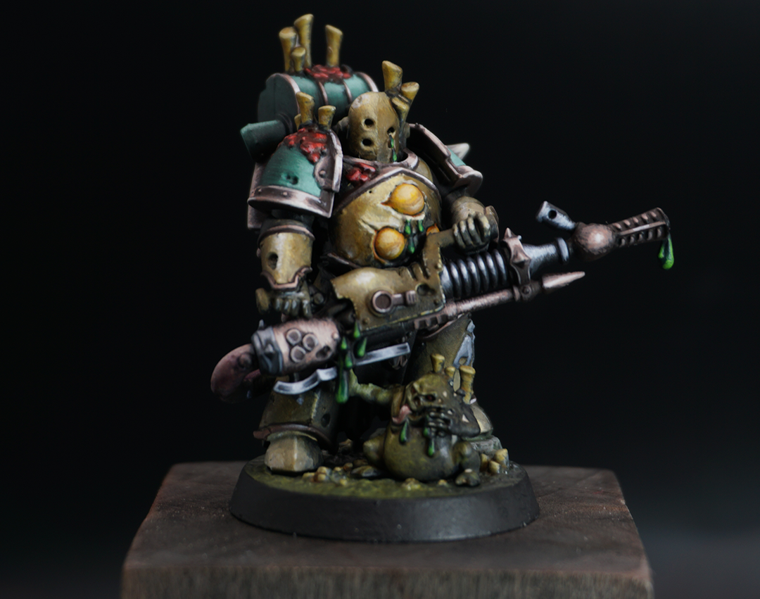 A painted miniature figurine of a heavily armored soldier holding a large gun, with a dark background.