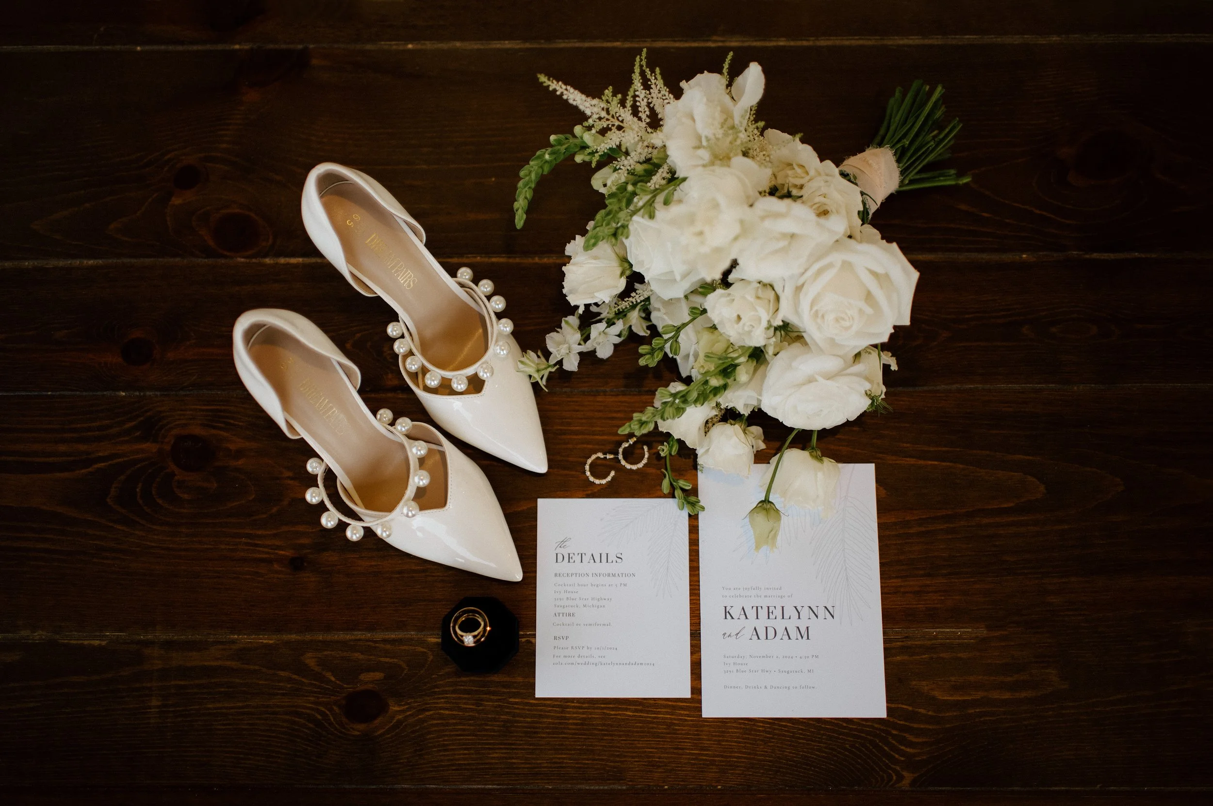 Wedding detail flatlay with bouquet, jewelry, shoes, and invitations from a Michigan wedding