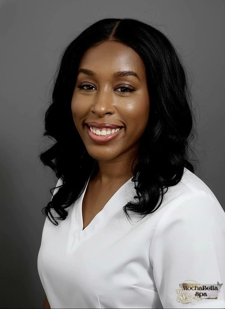 Professional lash extension artist headshot of a smiling woman wearing a white blouse against a gray background