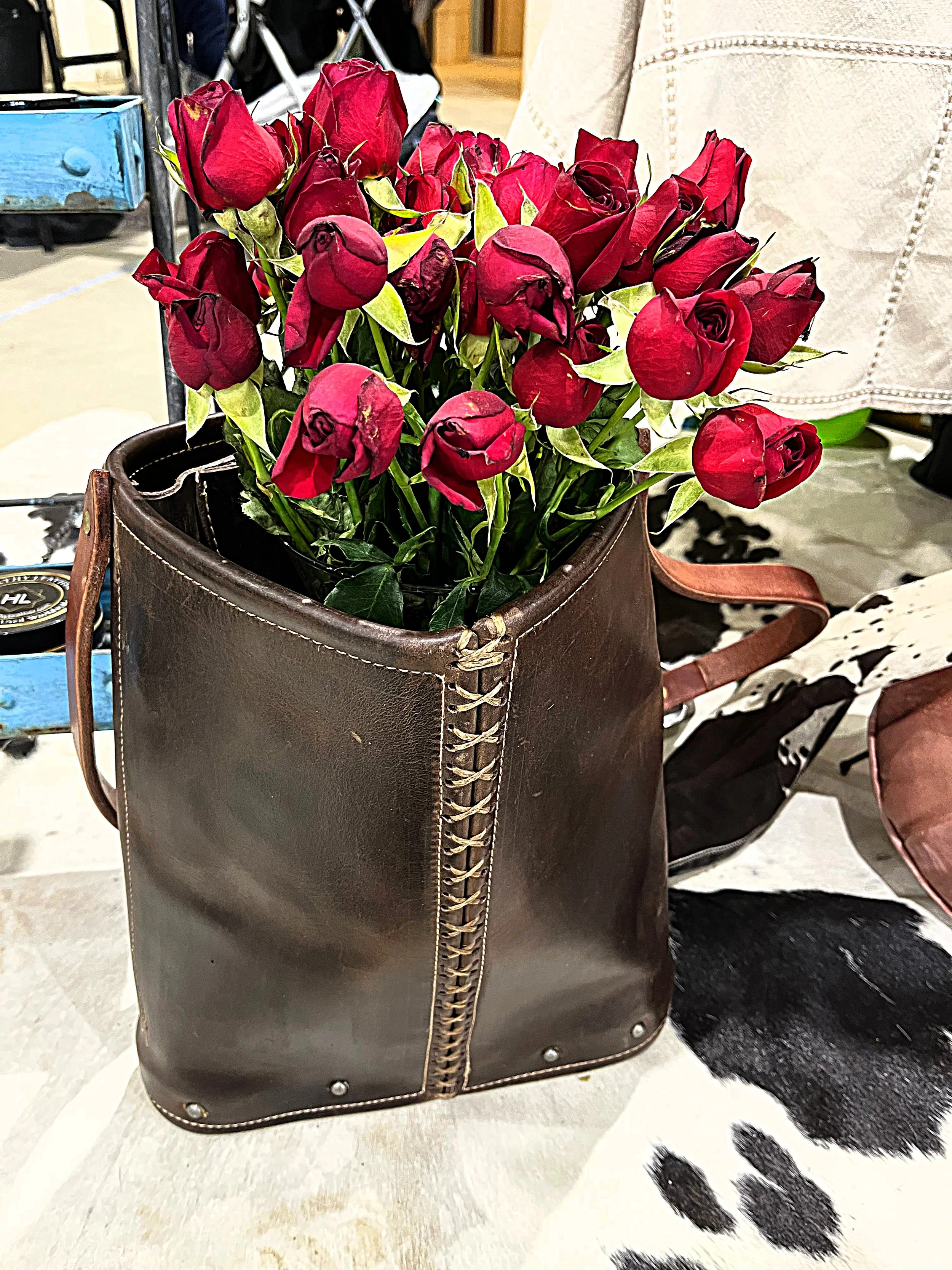 A gorgeous handmade leather tote bag that has had an application of Healthy Leather Premium Leather Care.  The bag contains a boquet of red roses.