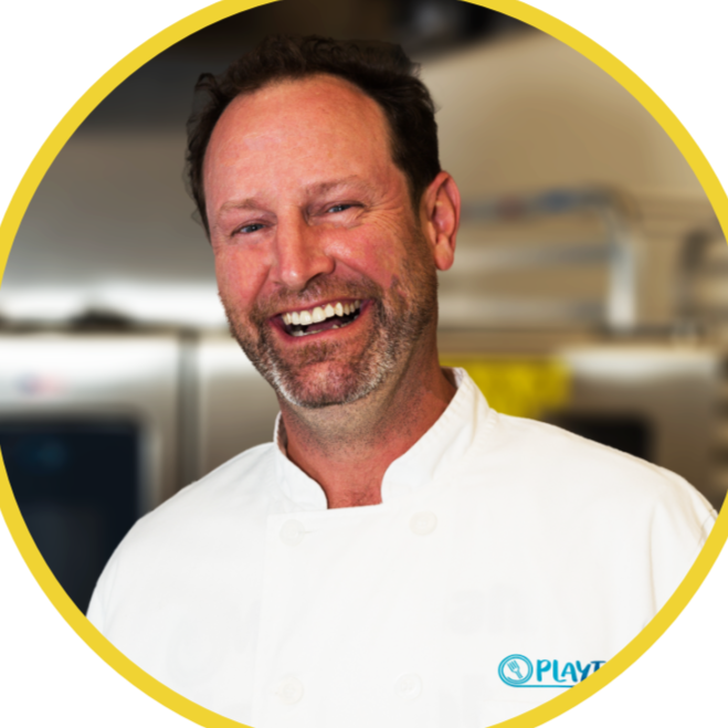Chef laughing in a kitchen for a company that offers cooking classes and food experiences.