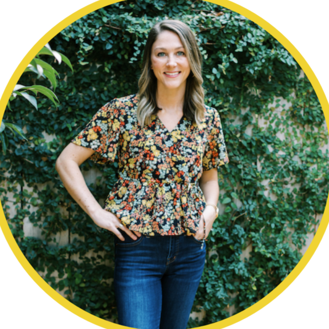 Woman in floral top and jeans standing in front of leafy background for a company that offers cooking classes and food experiences.