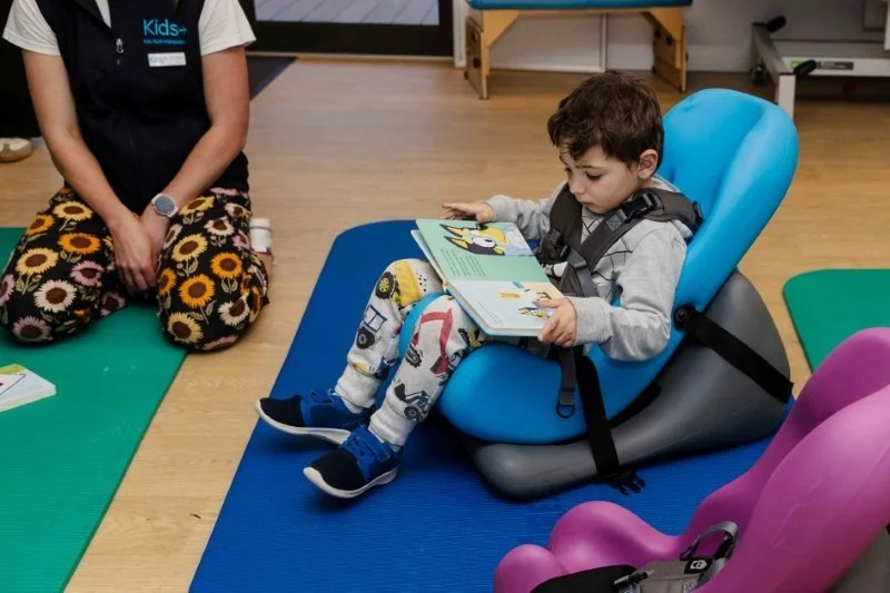 young boy in upright chair reads a book