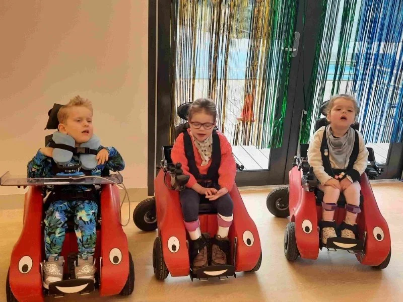 three children in a line using wizzy bug electric wheelchairs