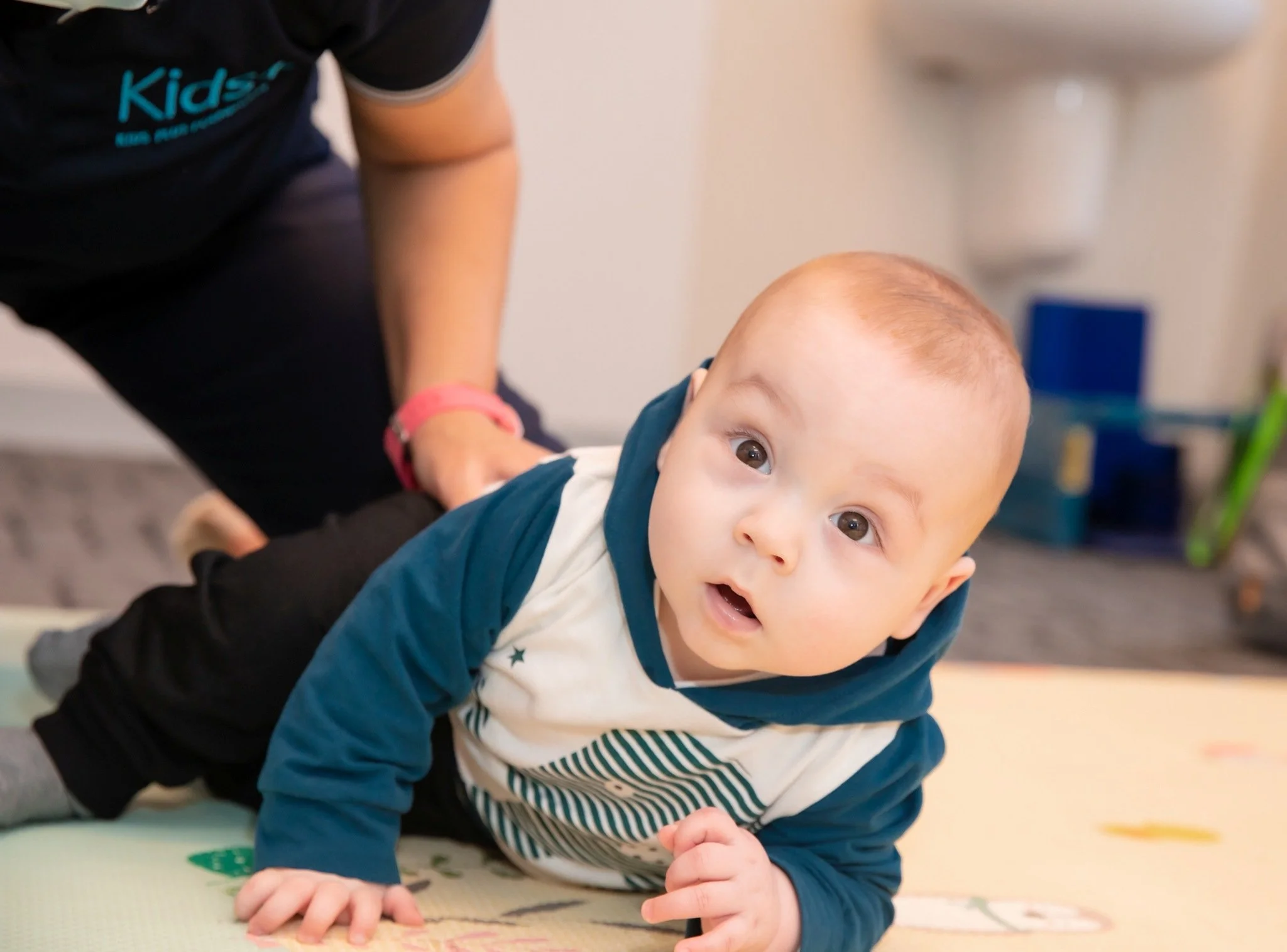 infant looks at camera as he is lying on his tummy on a playmat