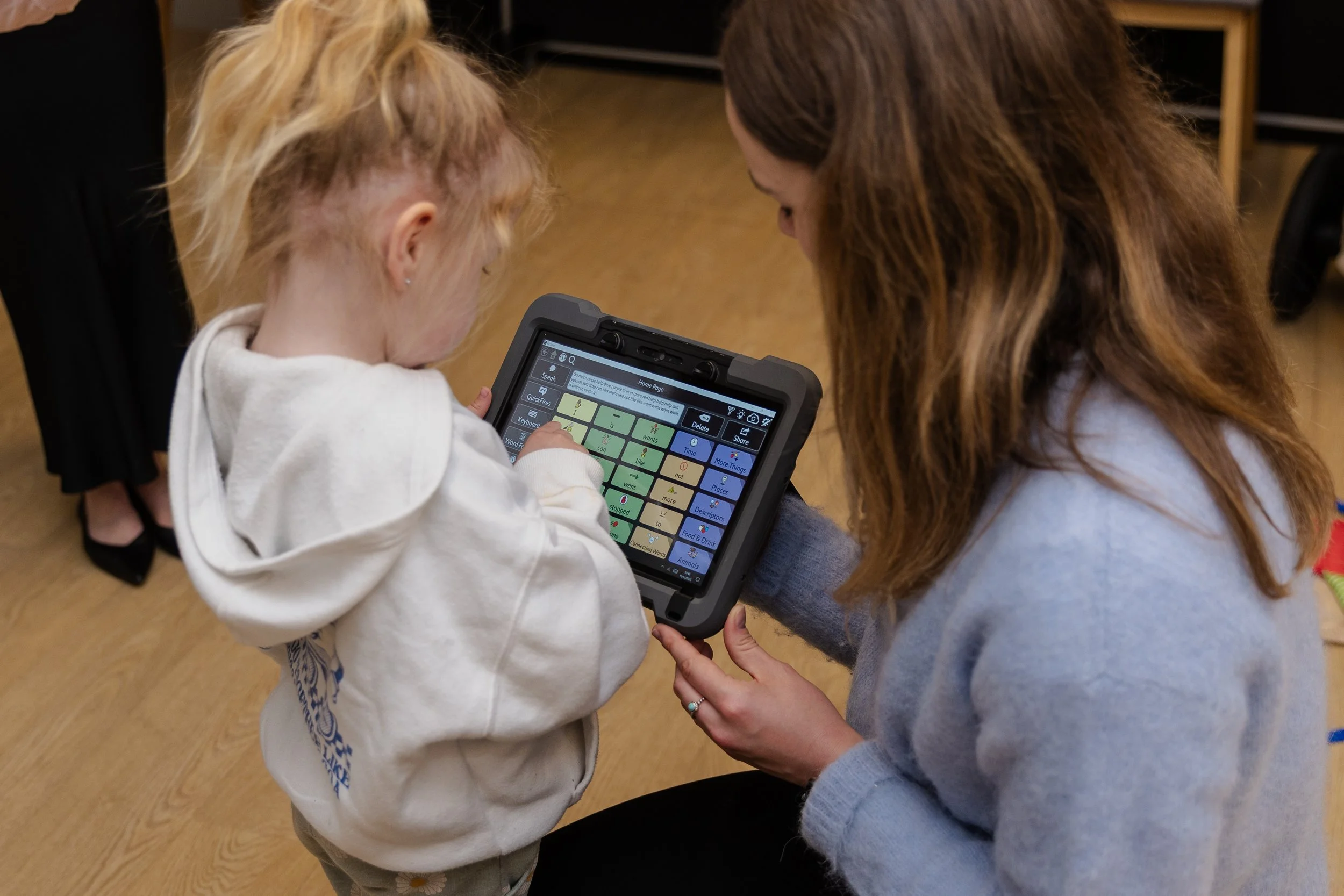 A young girl and a woman are looking at a tablet screen together indoors.