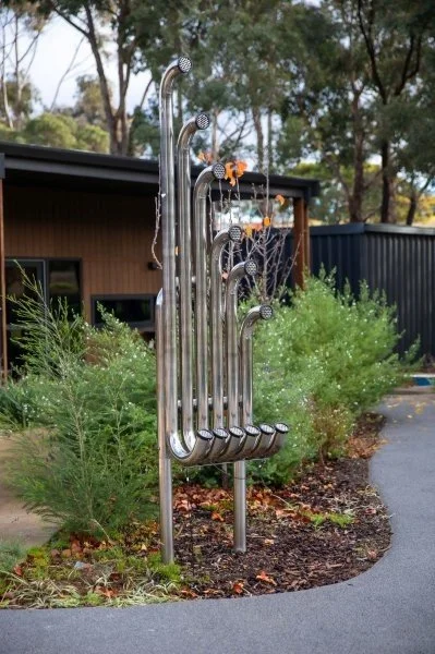 vertical installment of 6 silver sound pipes in playground
