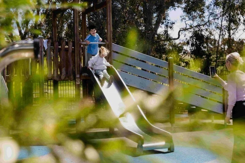 two children playing on a slide in an outdoor playground