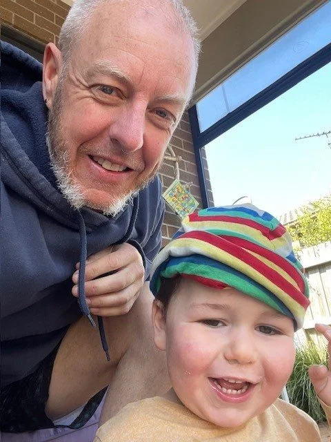 father and son smile for camera, dressed in winter clothing