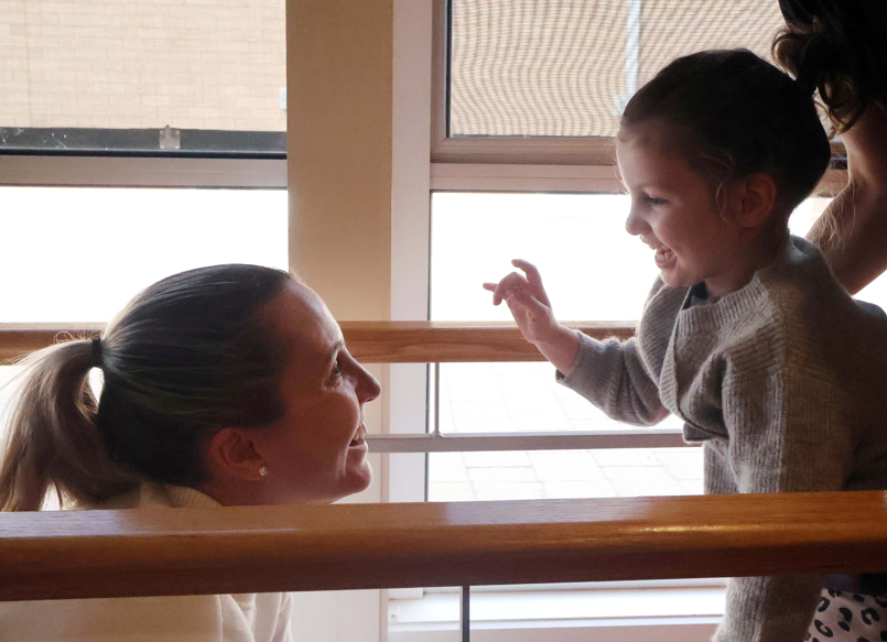side profile of mother and daughter smiling at each other