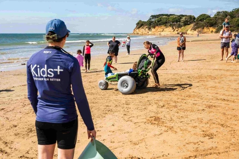therapist watches a group of children using a beach wheelchair