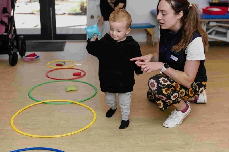 therapist and young boy play with hoops and throw a bean bag during a therapy session