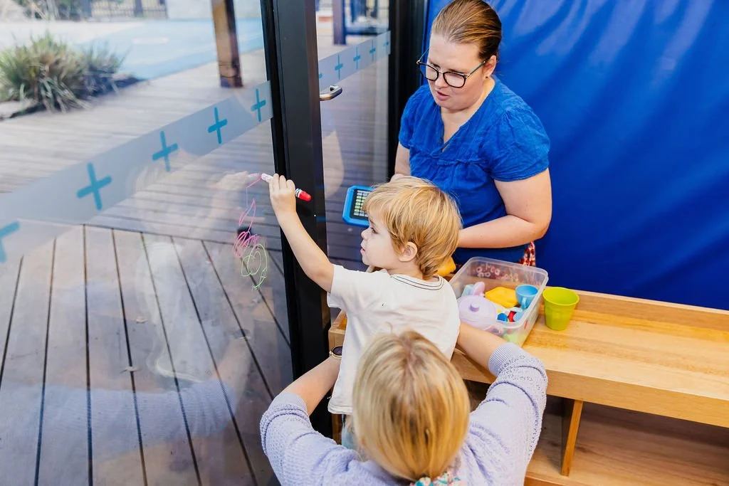 child draws on window during therapy session