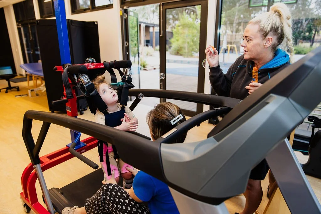 woman blows bubbles for young girl during a physiotherapy session at kids plus