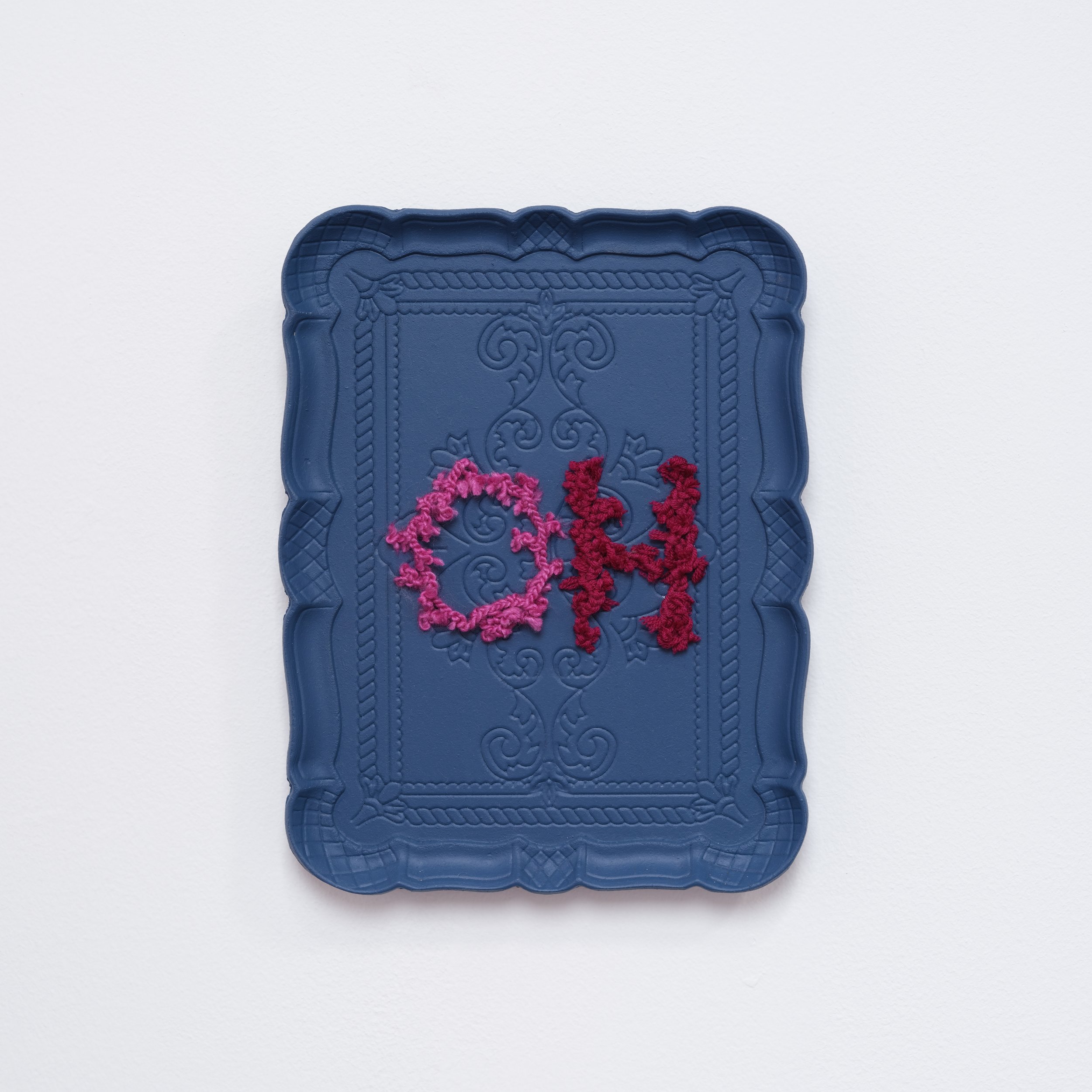 Decorative blue tray with the word OH in pink and red yarn