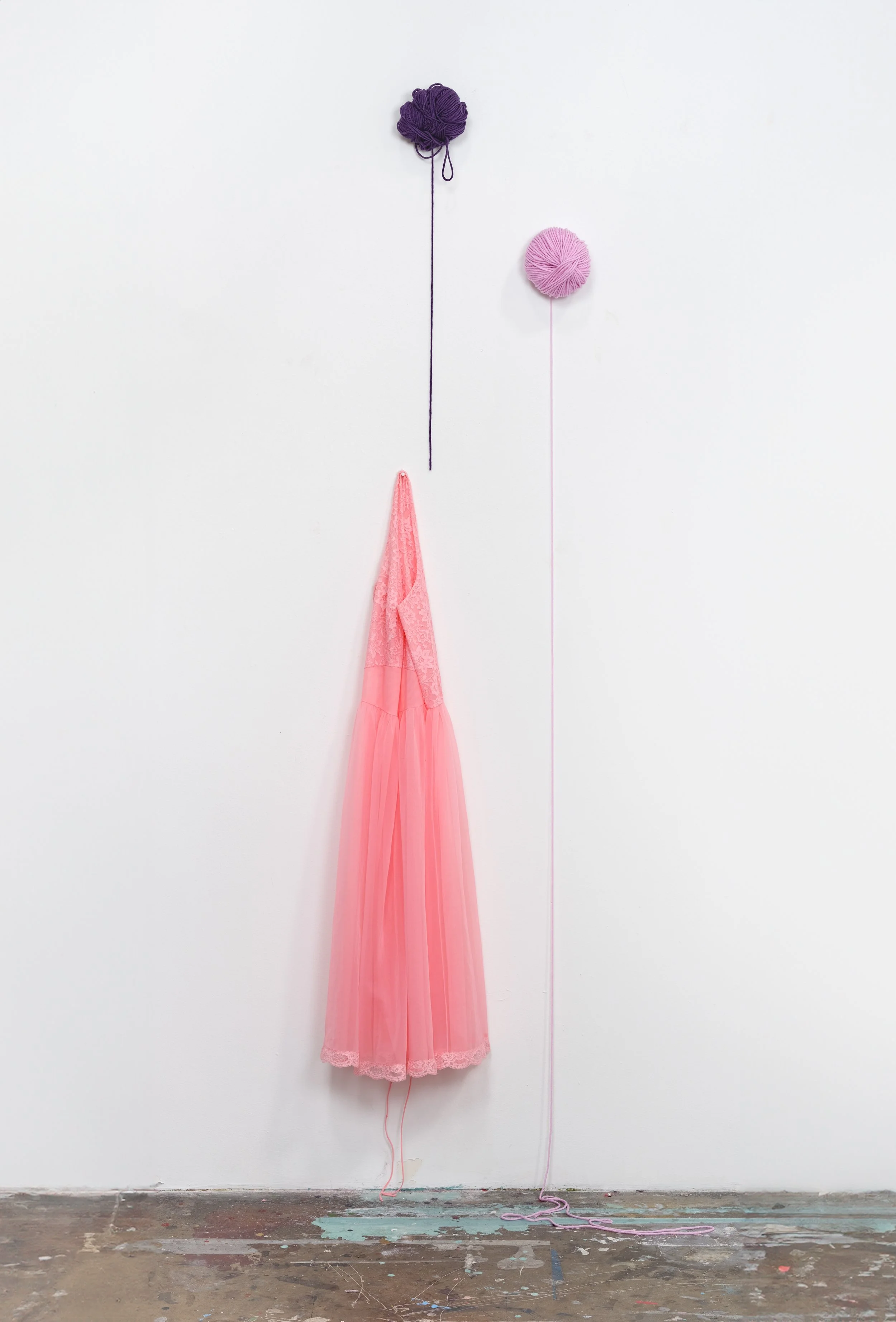 Found vintage salmon pink dress hangs along with purple and pink yarn
