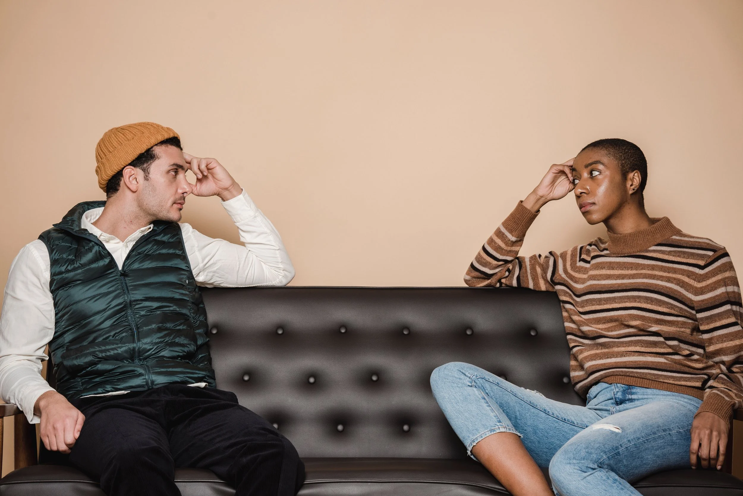 A visibly frustrated couple make eye contact on a couch