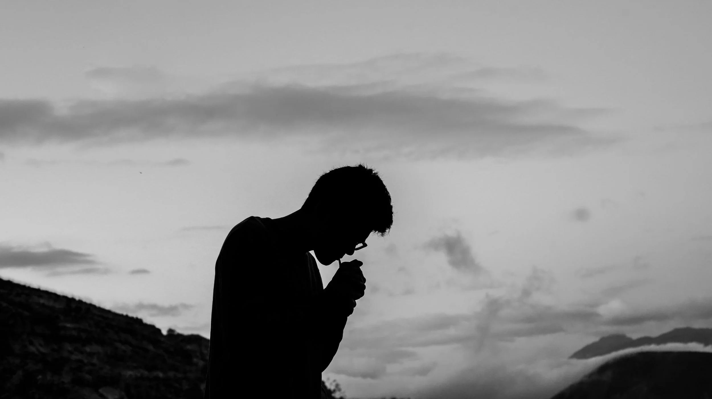 Black and white silhouette of a man smoking something.