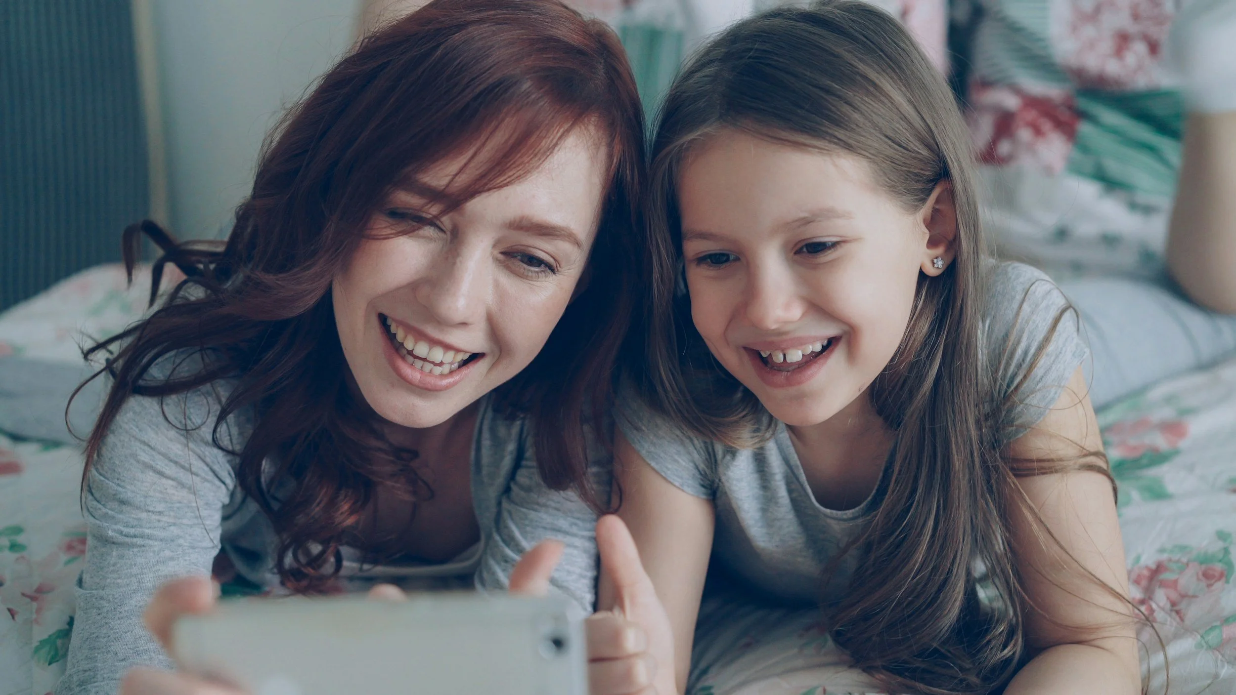 A child and her teen sister are smiling and taking a picture together.