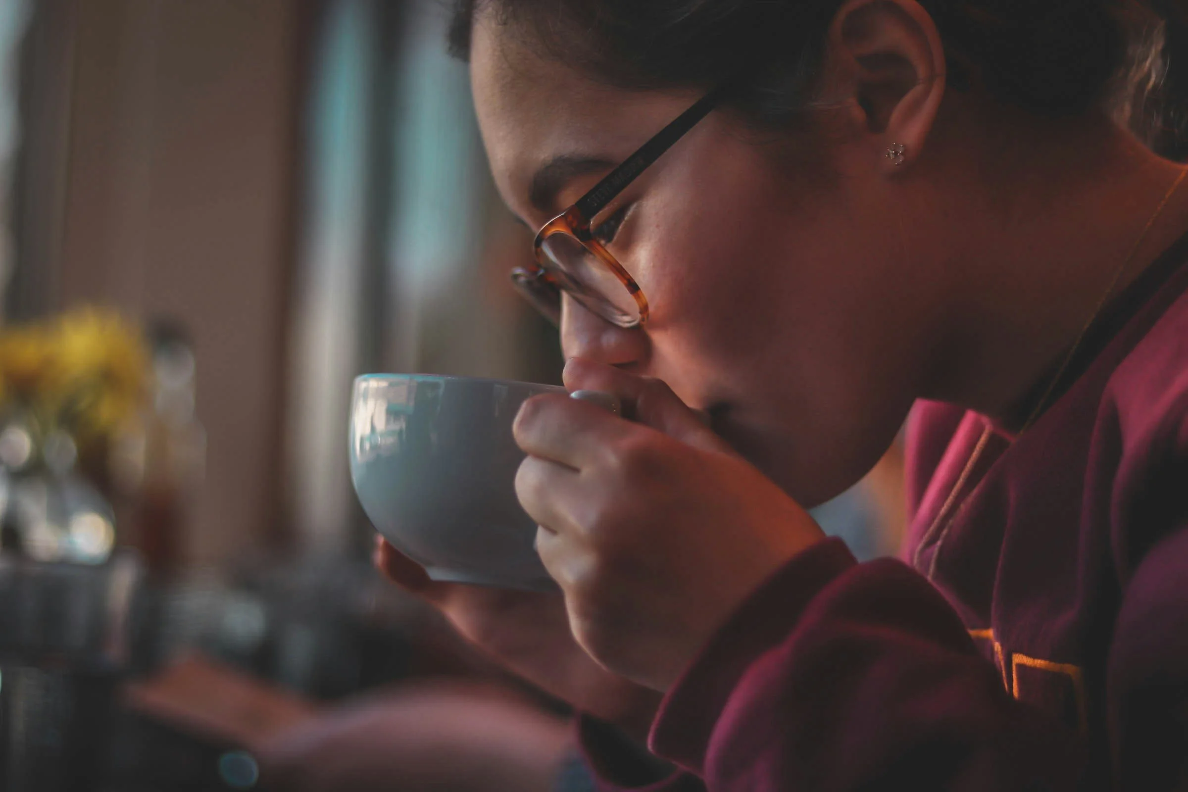 A person drinking tea from a blue mug feeling calm