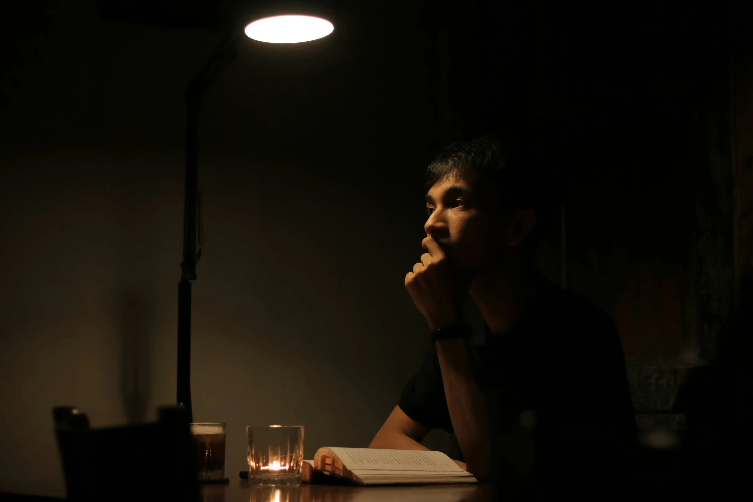 A person sits awake at a table late at night unable to sleep