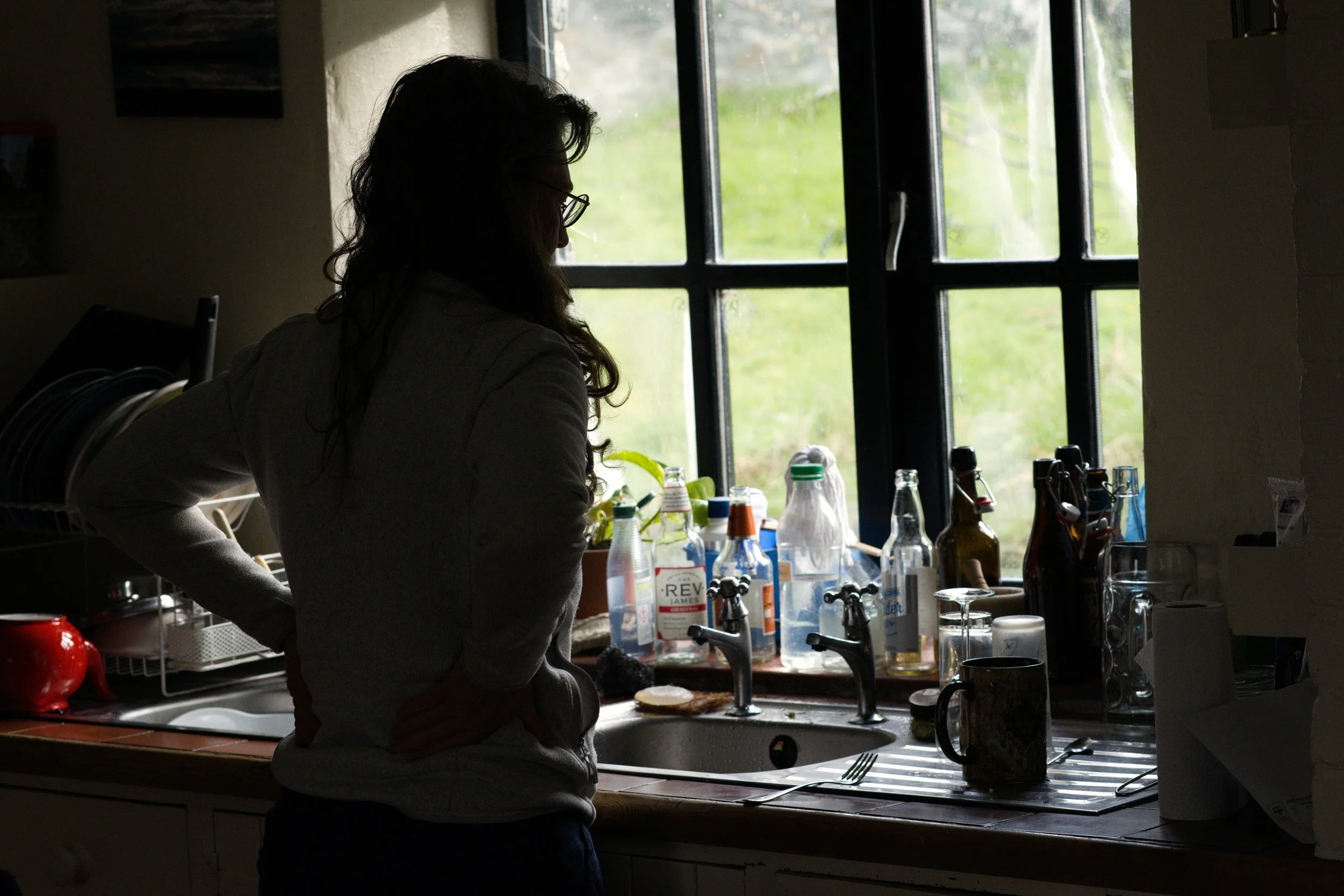 Person standing alone in a kitchen showing signs of emotional burnout and exhaustion