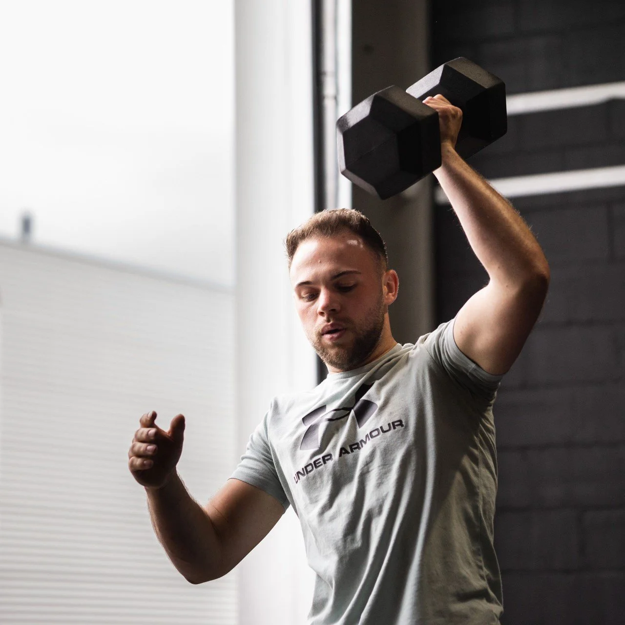Lid van Black Oak CrossFit Turnhout voert een geconcentreerde dumbbell workout uit tijdens een groepstraining.