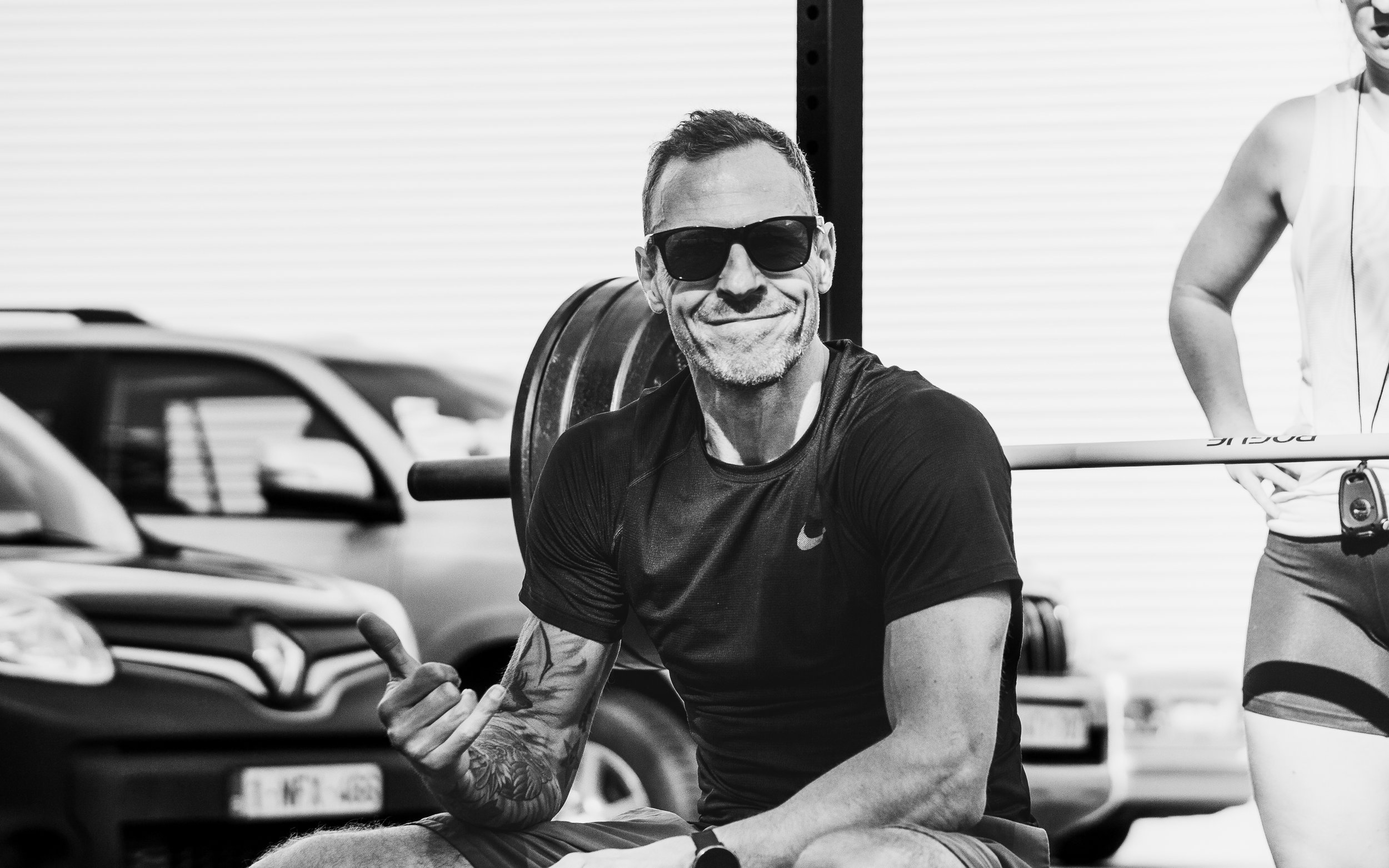 Coach Mike Luyten van Black Oak CrossFit Turnhout geeft een duim omhoog tijdens een outdoor training bij het rig.