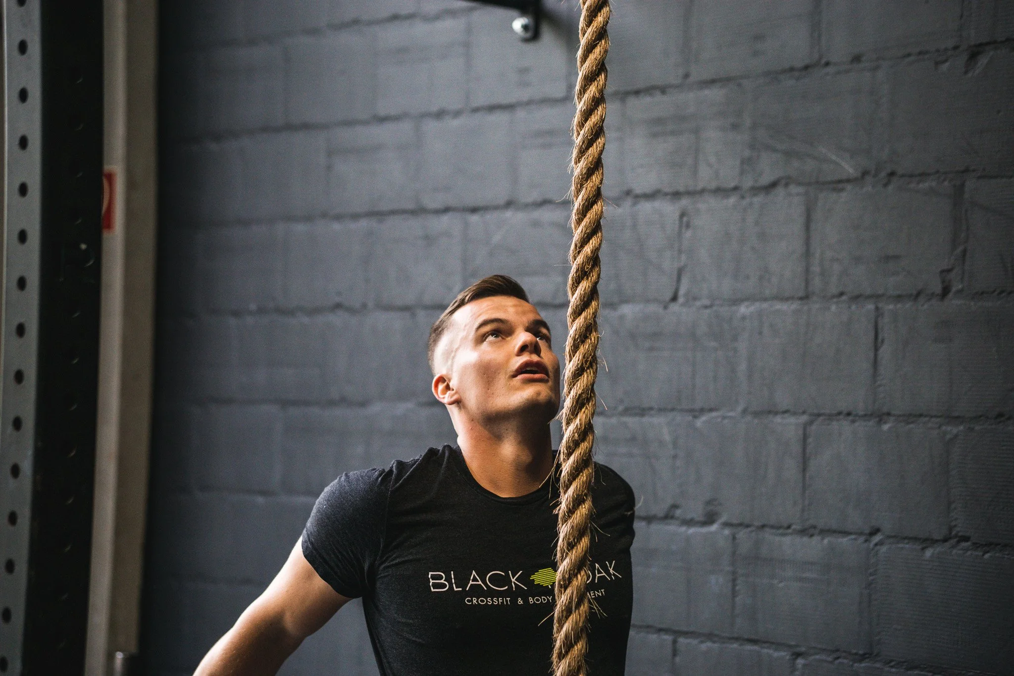Gefocuste atleet bij Black Oak CrossFit Turnhout bereidt zich voor op een rope climb training in de box.