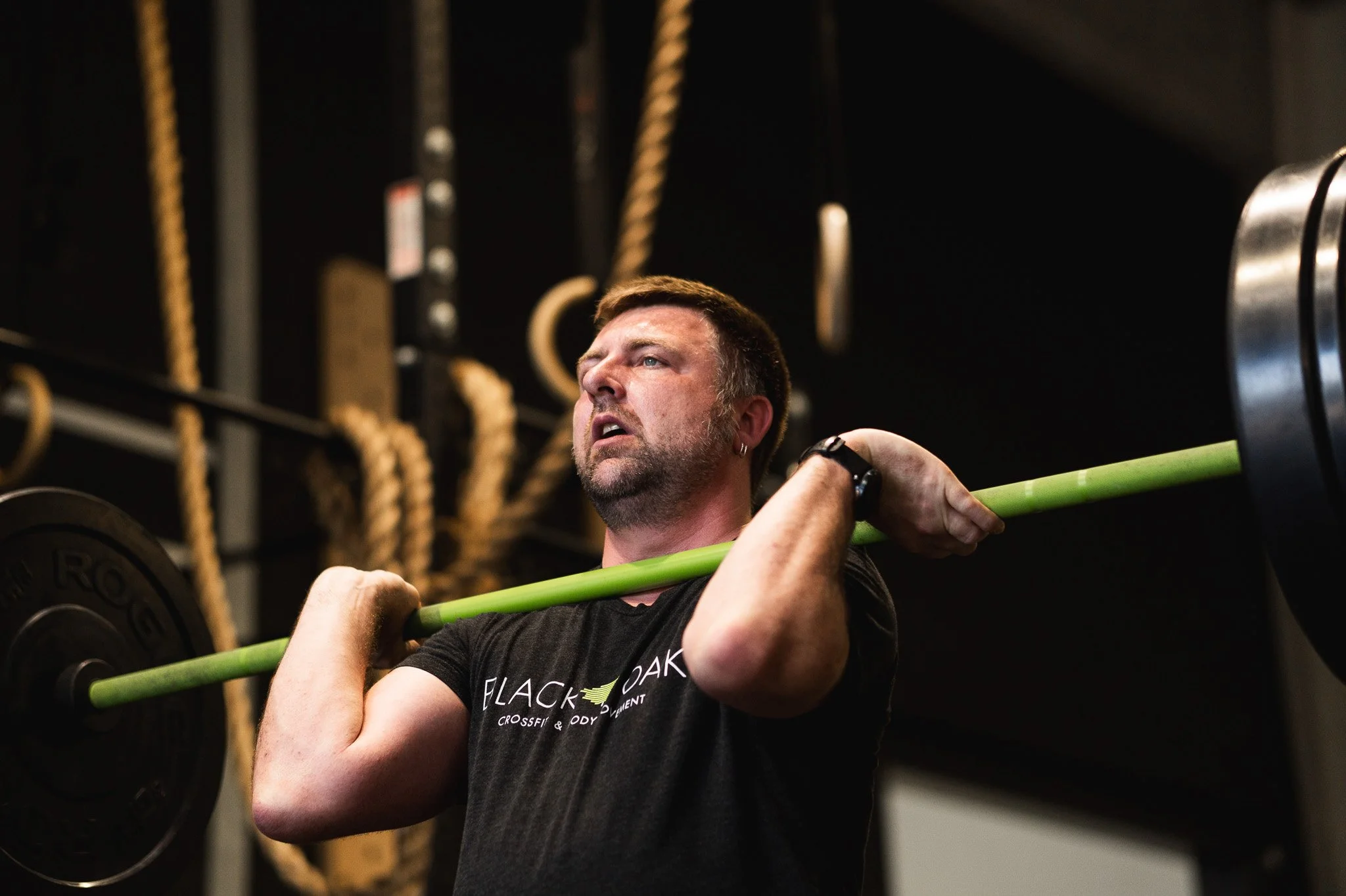 Gefocuste atleet voert een olympische gewichthef-oefening uit met een barbell bij Black Oak CrossFit Turnhout.
