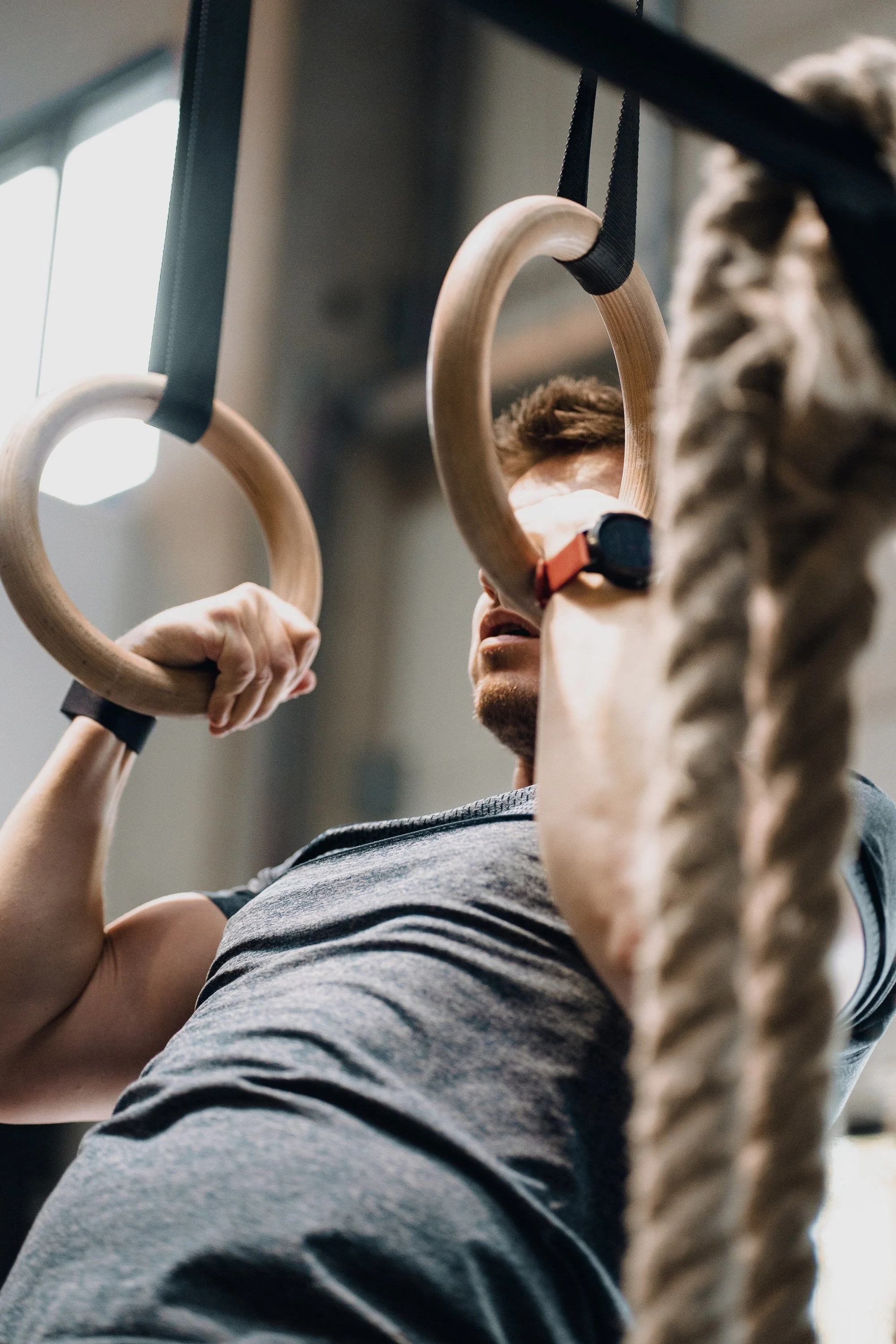 Atleet bij Black Oak Turnhout voert een gecontroleerde transitie uit aan de ringen tijdens een gymnastics les.