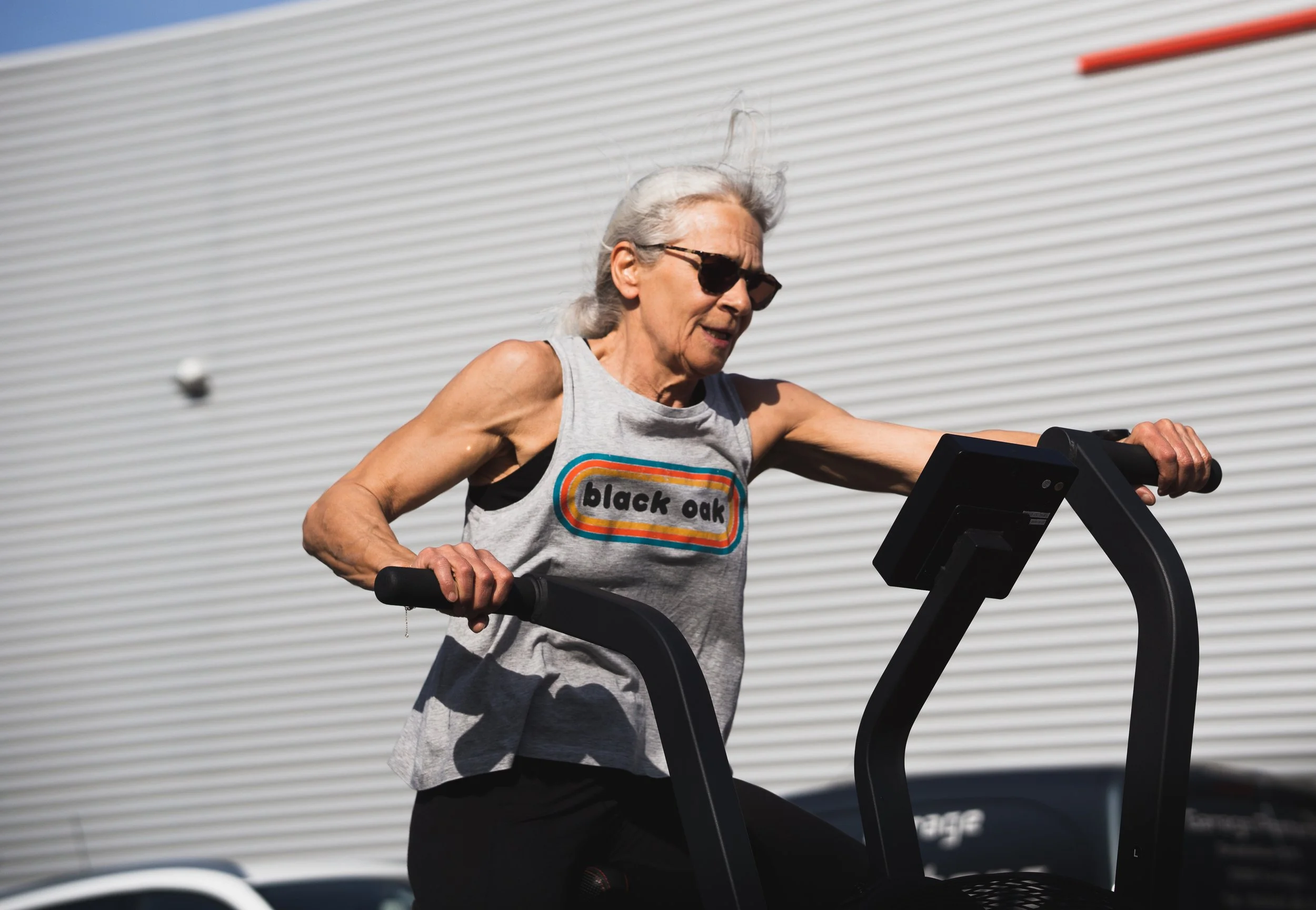 Gefocuste atlete in actie op een airbike tijdens een intense Sweat 30-training bij Black Oak CrossFit Turnhout voor maximaal resultaat.