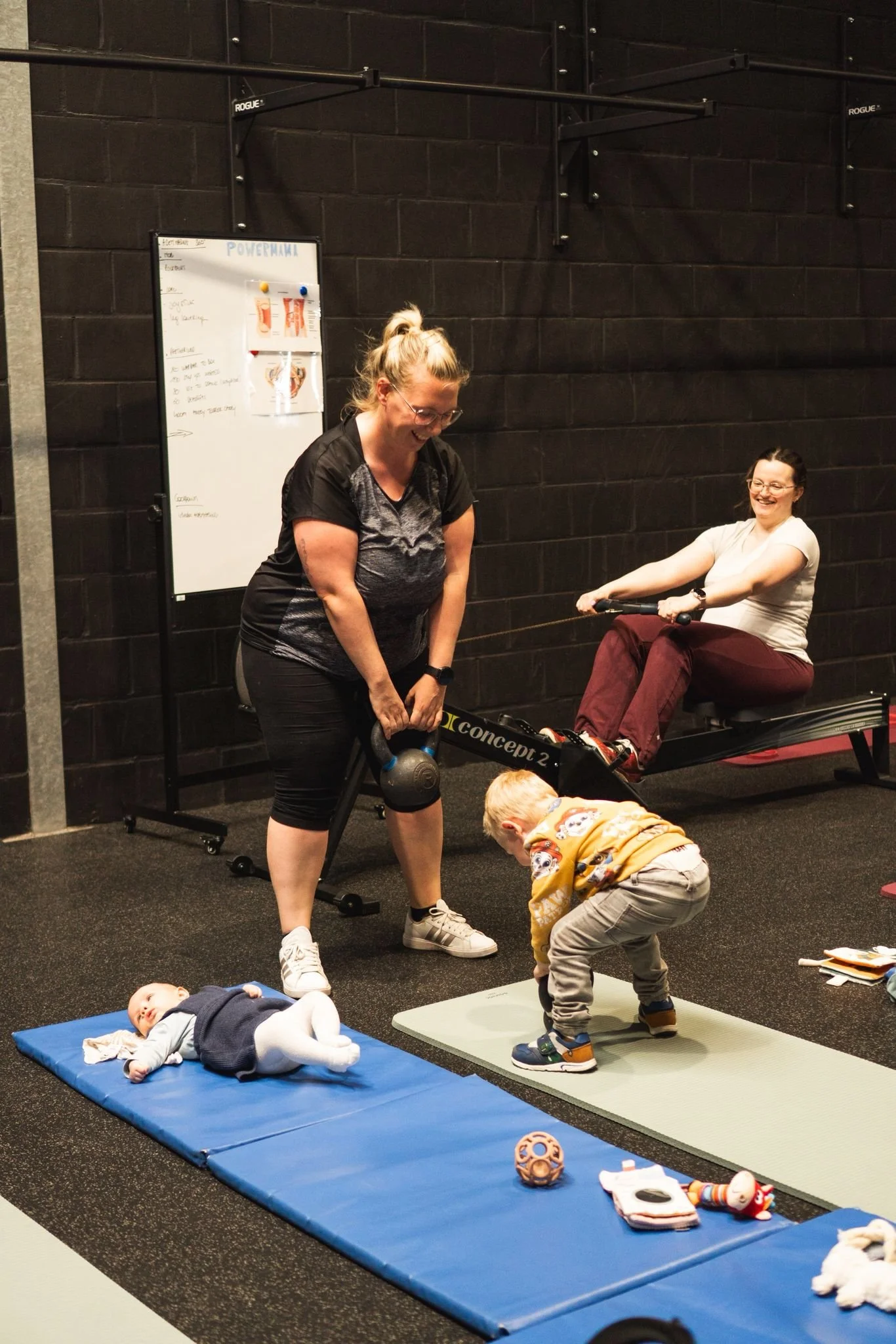 Moeders trainen samen met hun baby's en kinderen tijdens een PowerMama post-natale les bij Black Oak.