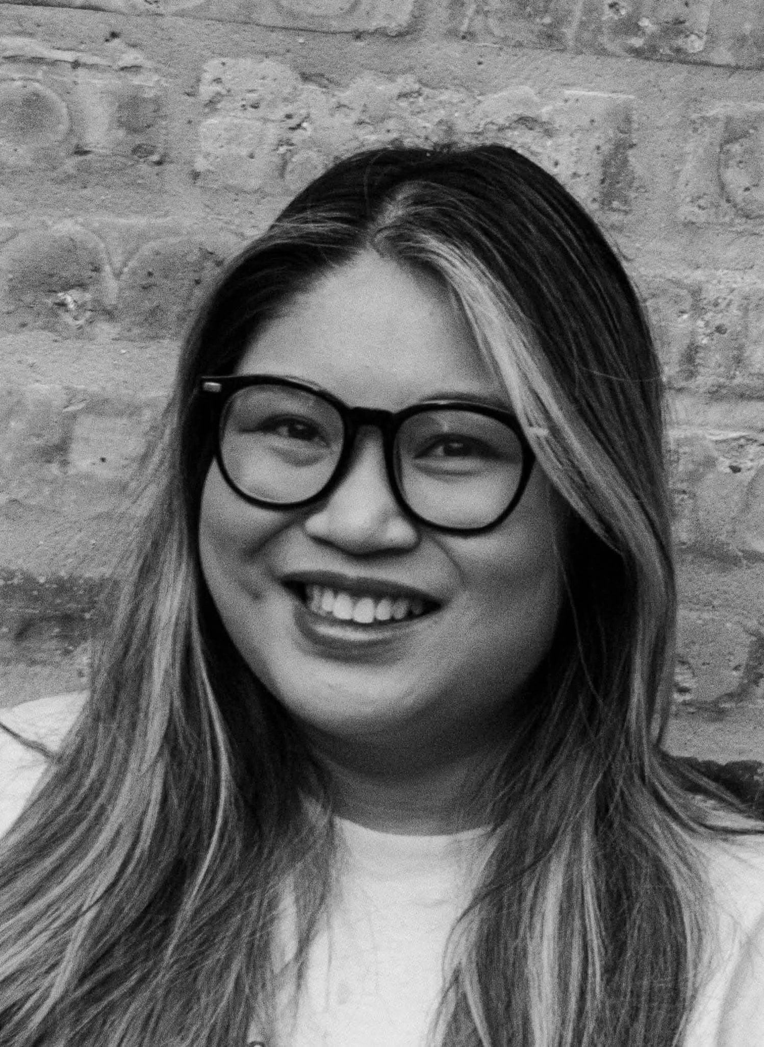 black and white photo of a smiling woman with long, dark hair with light highlights framing her face