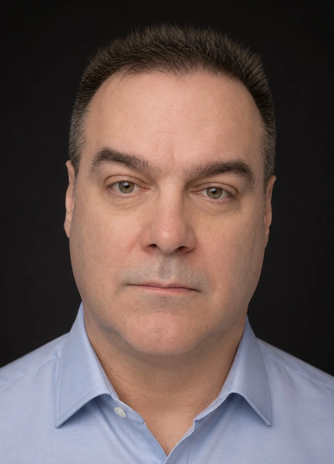 Portrait of a man wearing a blue shirt and looking into the camera