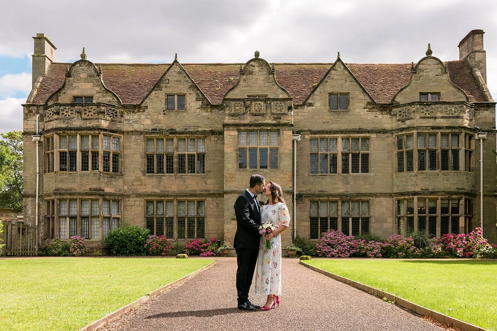 a bride and groom stood embraced in front of st johns house warwick