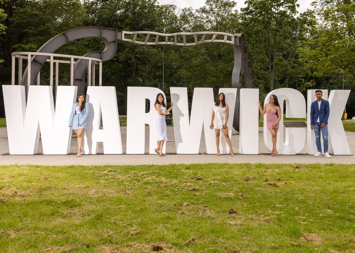 A group of graduates infront of the Warwick sign at Warwick University