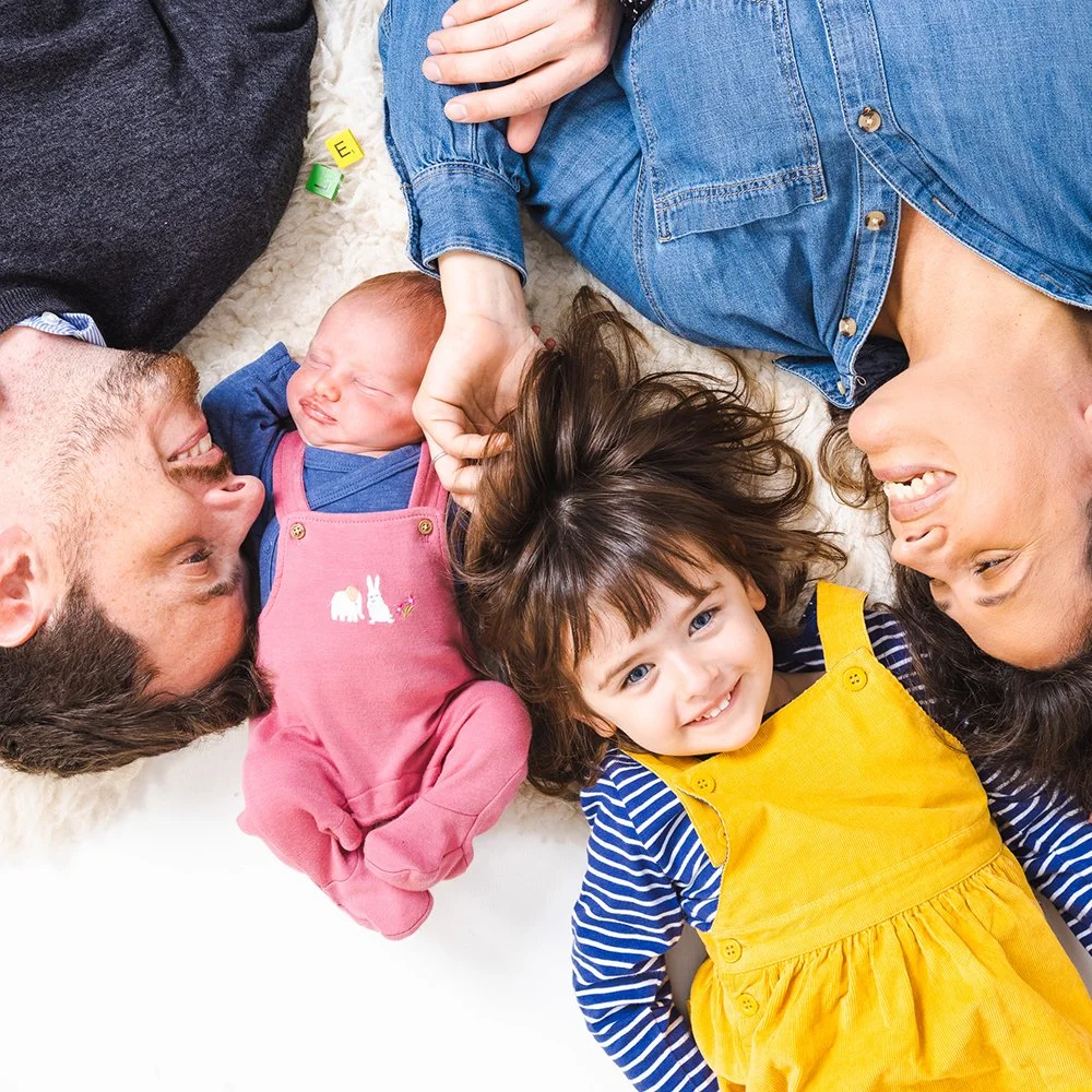 Family lying on the floor in a circle, smiling and enjoying time together.
