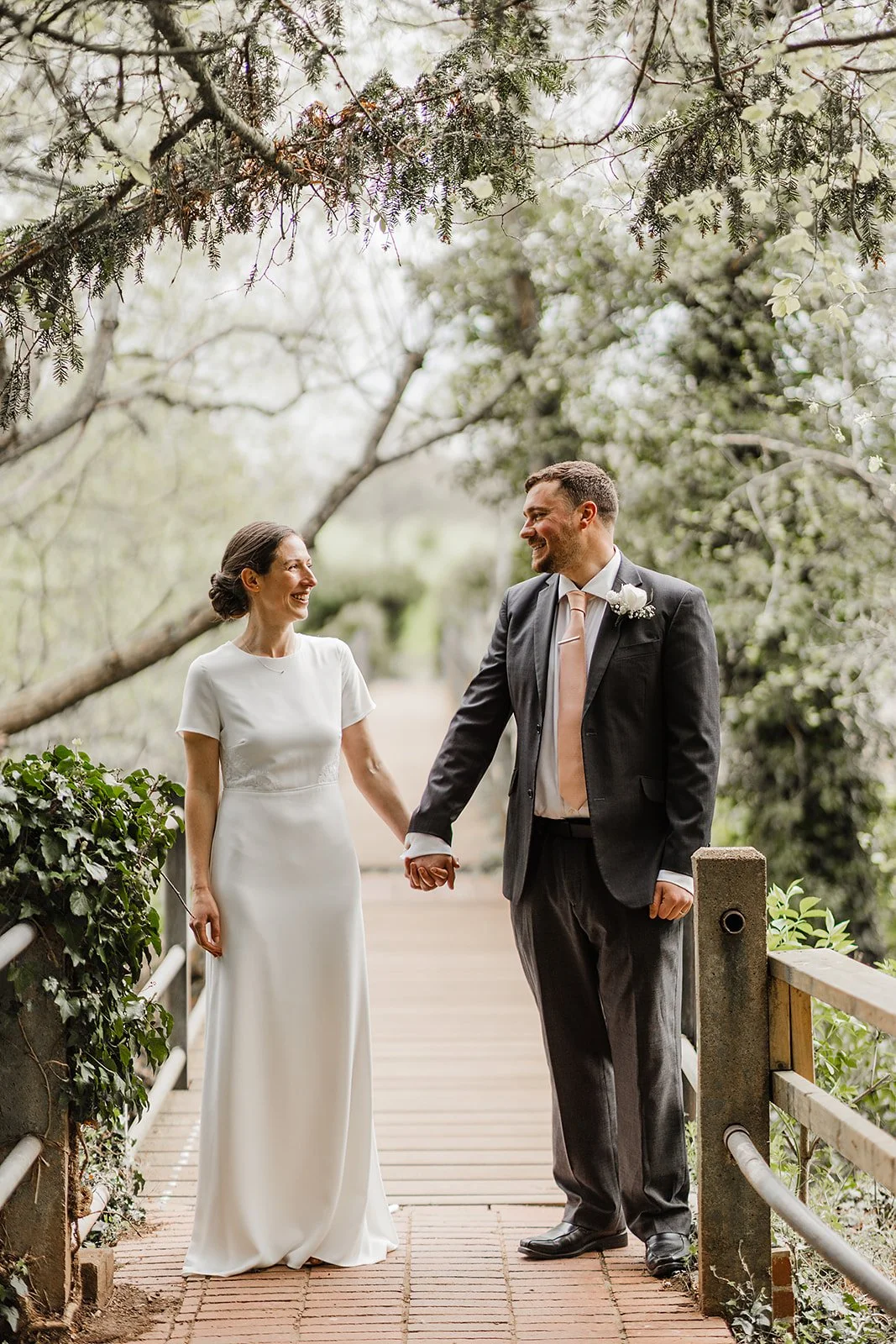 a bride and groom looking at each other on a bridge