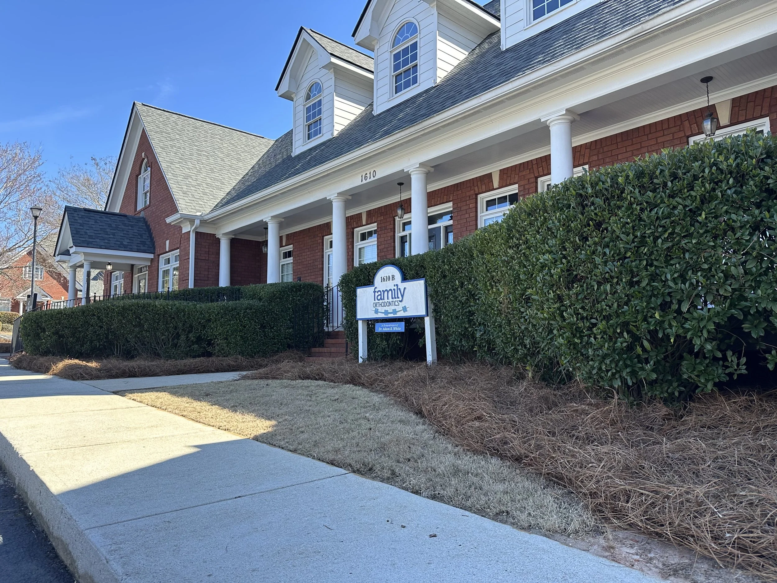 Residential style store front side walk with clean dormant sod, trimmed shrubs, and fresh pine straw