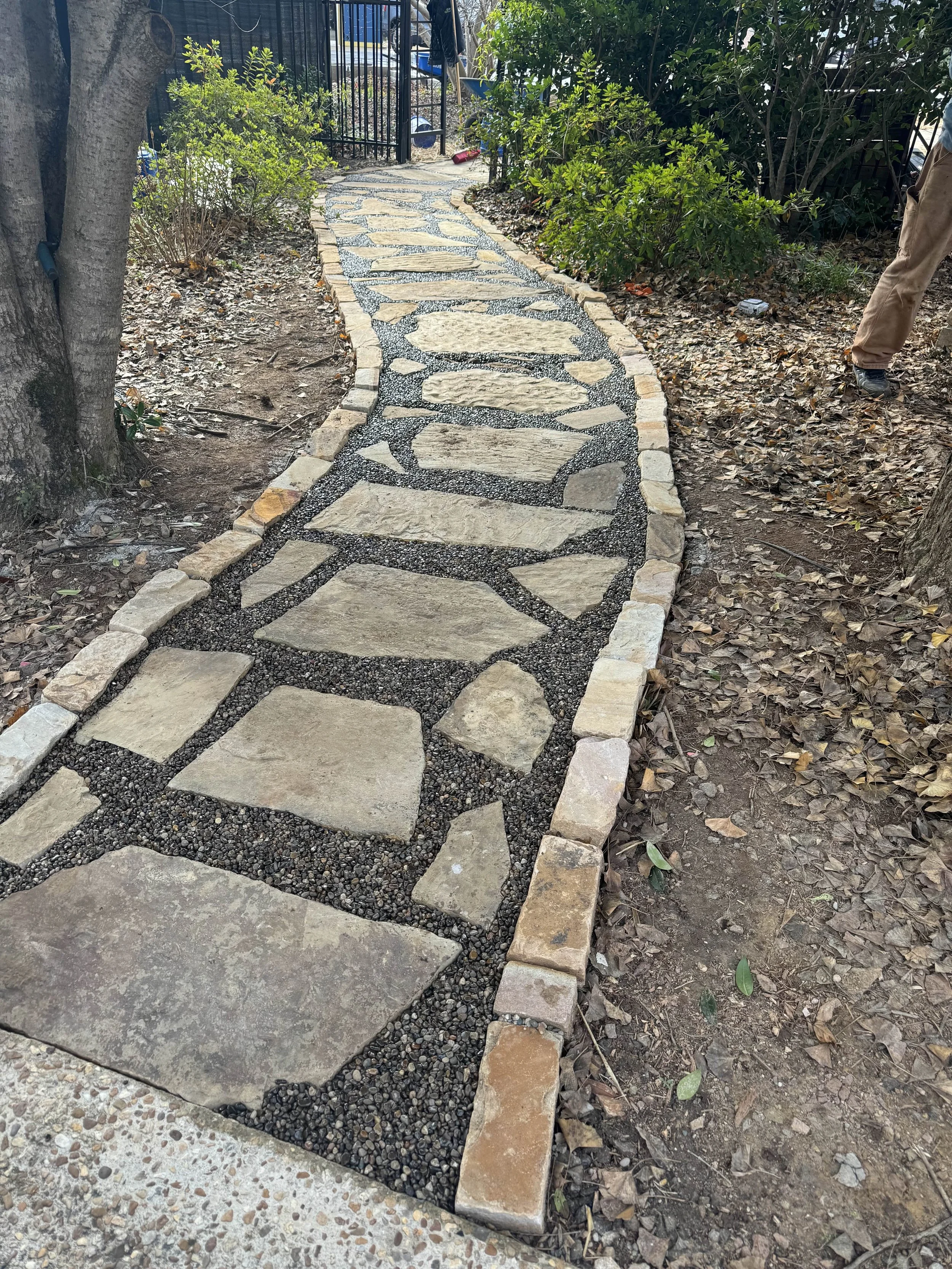 Flagstone and gravel pathway bordered with stacked stone edging through a wooded lot.
